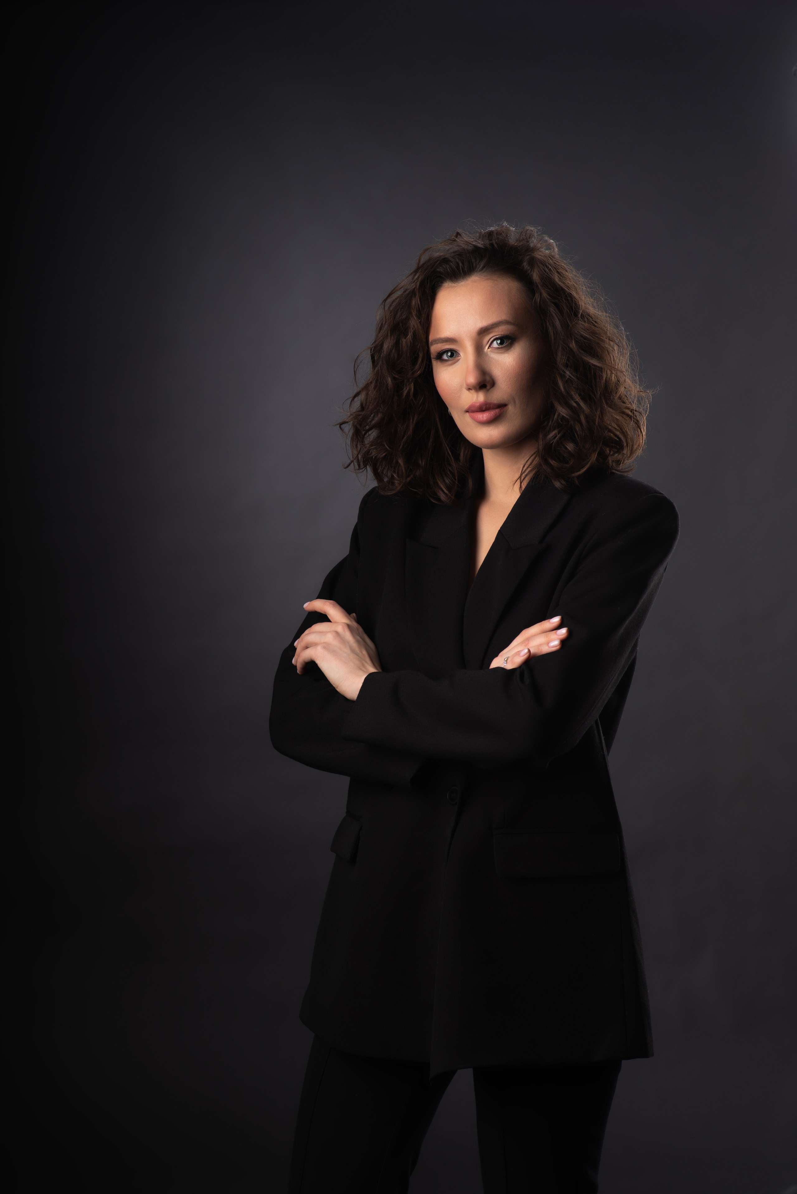 Деловой портрет молодой женщины с чёрном костюме с  прекрасной причёской. 