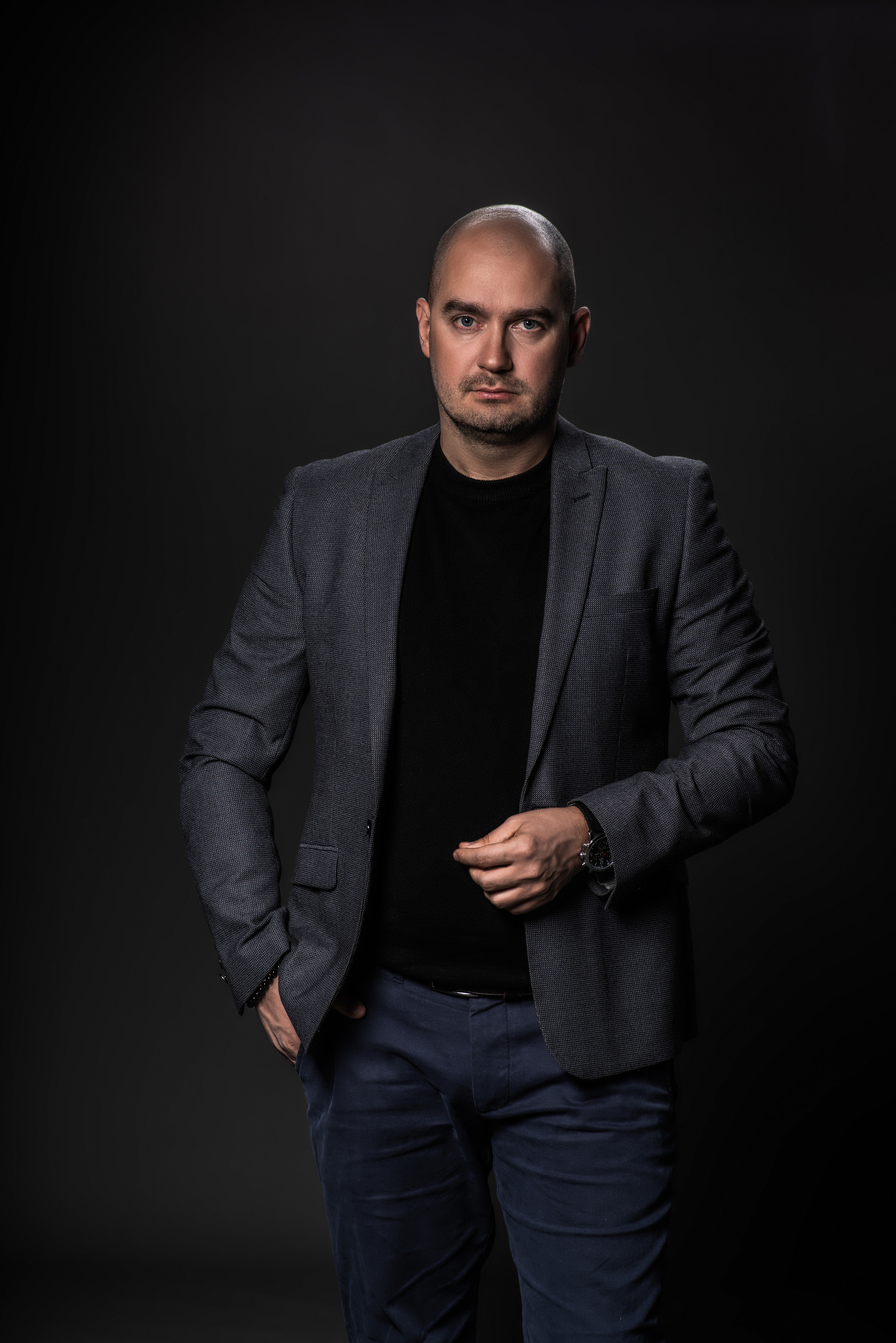 Деловой портрет молодого мужчины  в сером костюме на тёмном фоне в студии 