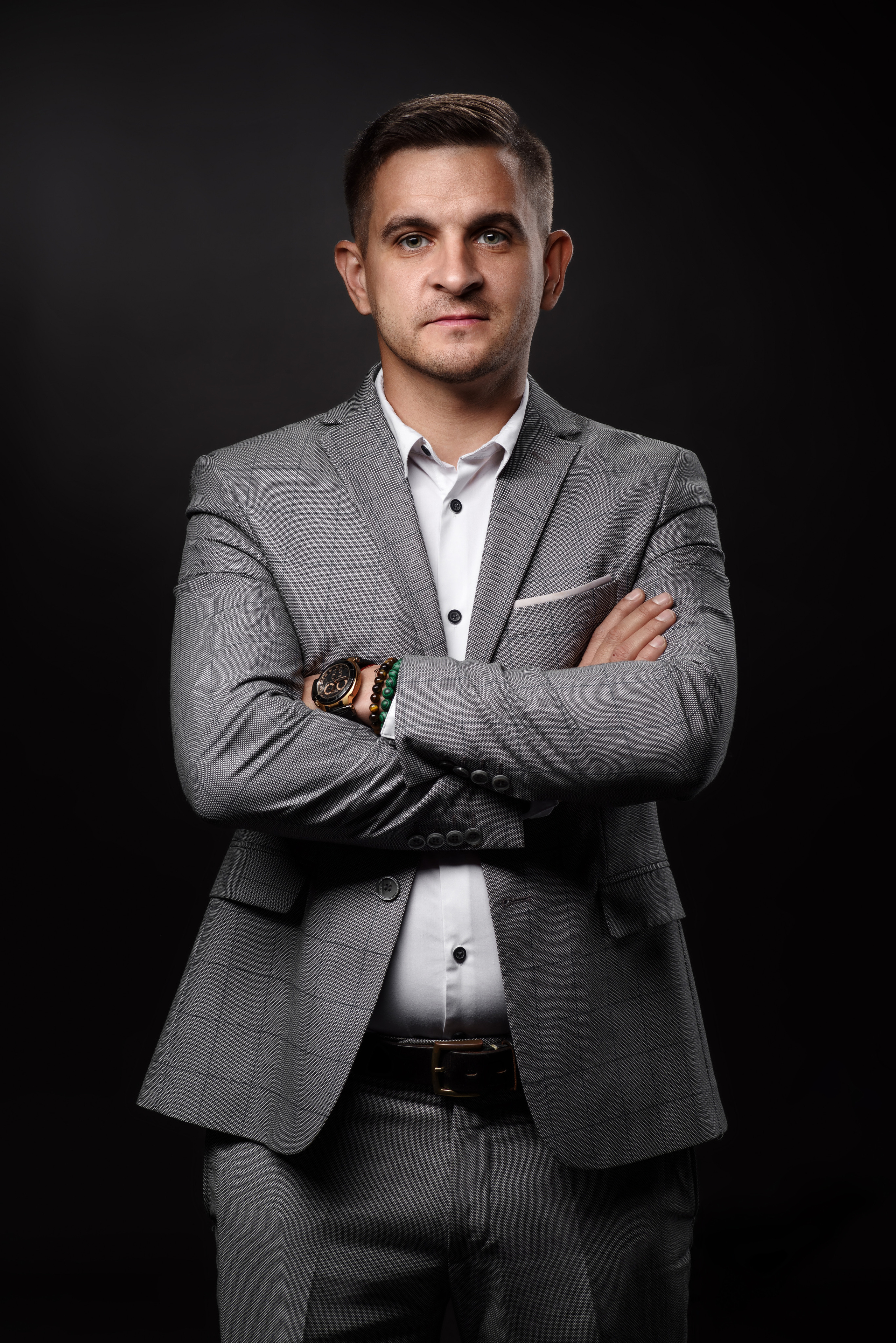Бизнес-портрет молодого человека в сером костюме на тёмном фоне