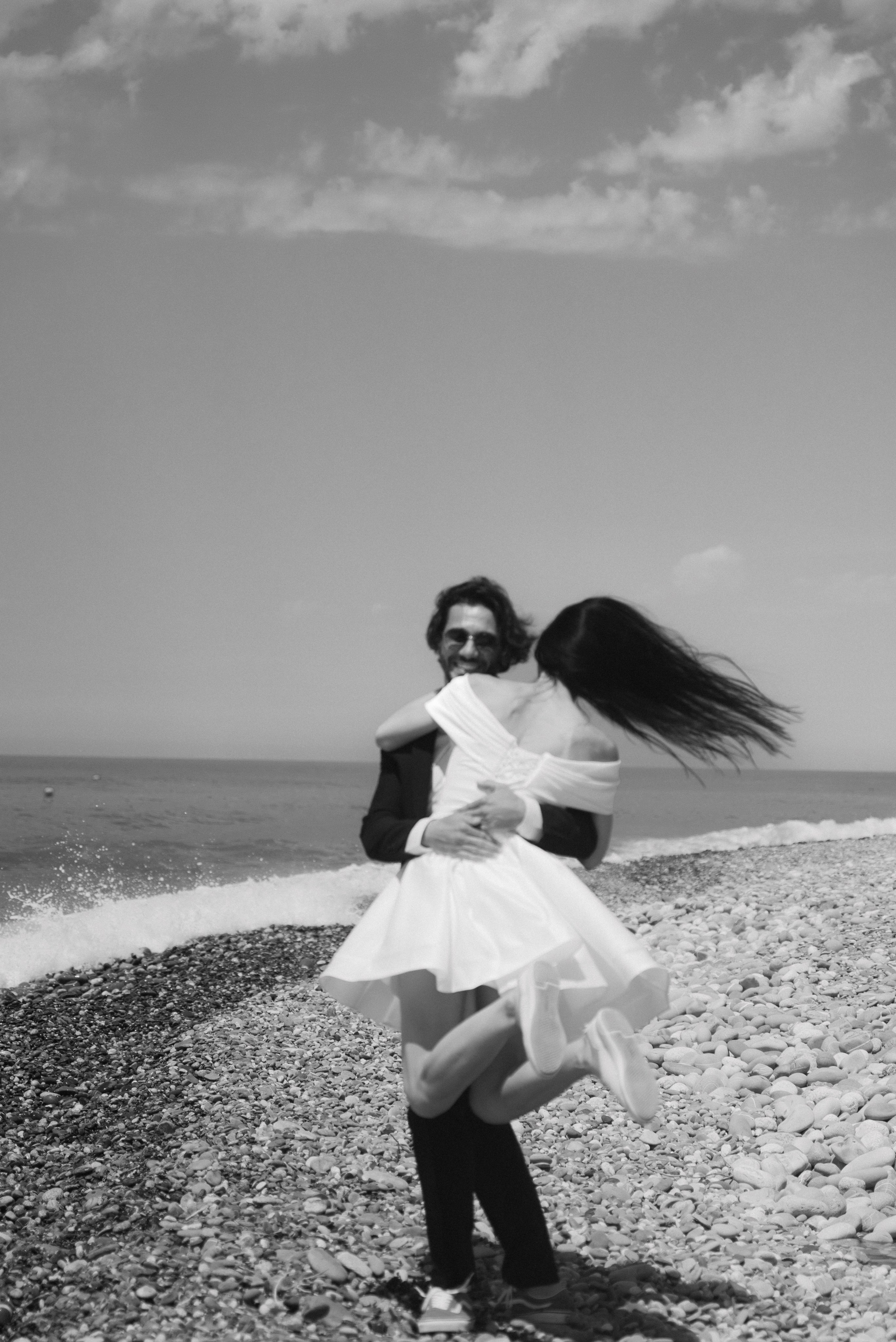 Романтичная фотосессия на пляже в Сочи для влюбленных чёрно-белый снимок где жених обнял невесту немного приподнял её и кружит 