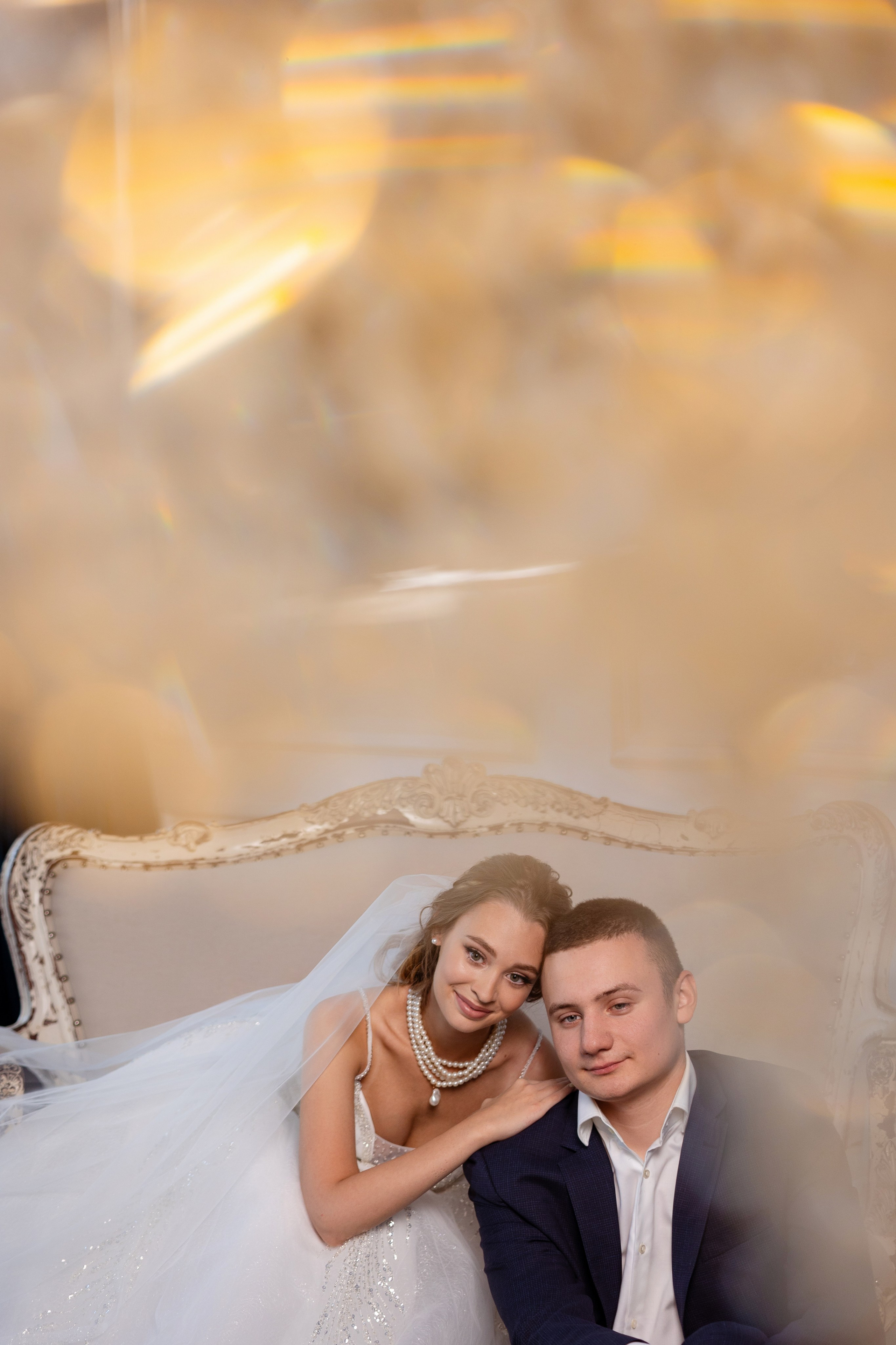 Молодые сидят на диване голова к голове.