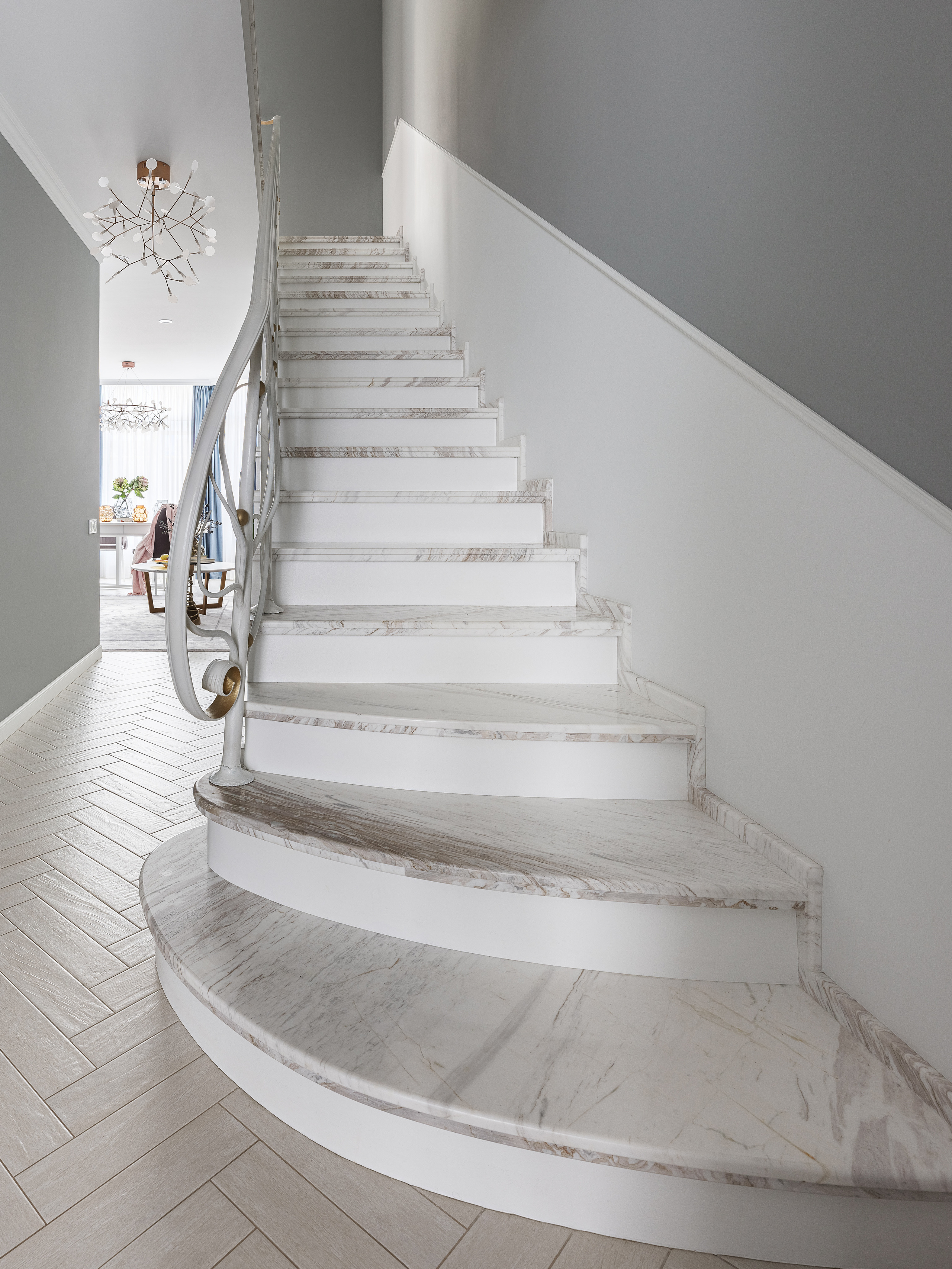Светлая мраморная лестница в современном доме с серой акцентной стеной и изящным перильным ограждением, интерьер выполнен дизайнерами Светланой Олефиренко и Марией Морозовой, фото Сергея Денисенко.