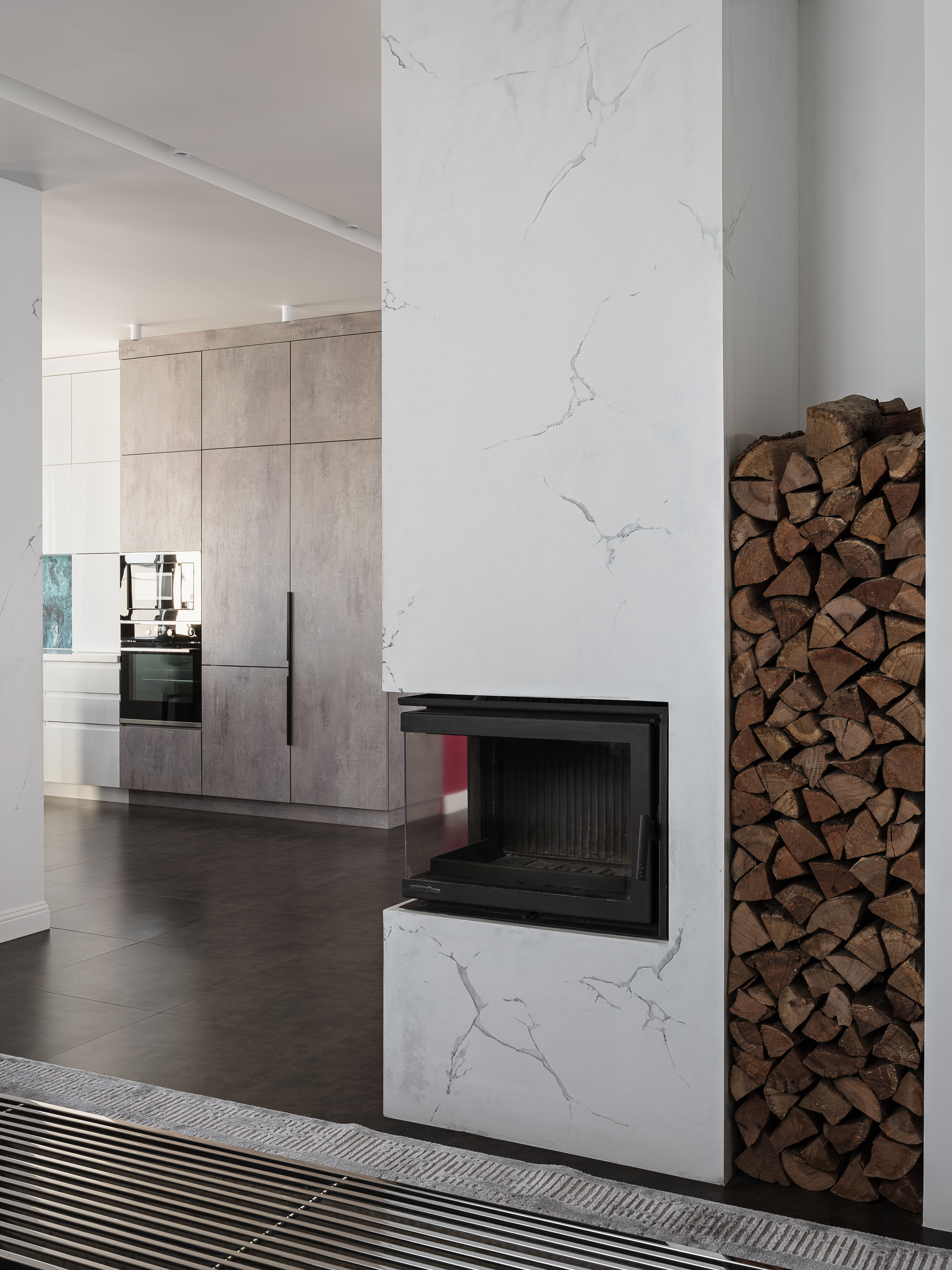 Современный камин с отделкой под белый мрамор и нишей для дров в интерьере кухни-гостиной с бетонными фасадами. Проект дизайнера Ирины Вольхиной, стилист Марина Чернышева, фотограф Сергей Денисенко.