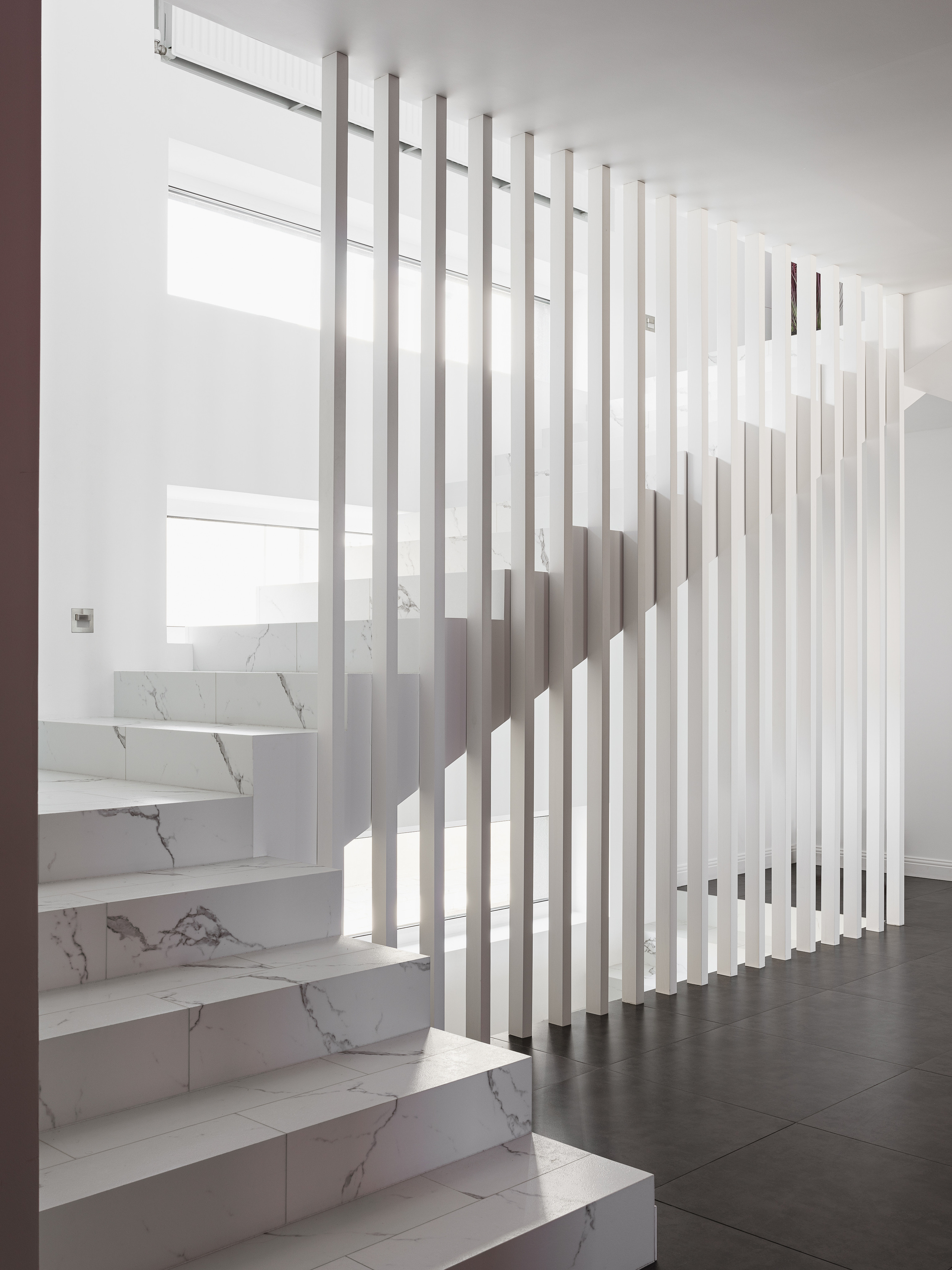 Белая лестница с мраморной текстурой и вертикальными перегородками в современном минималистичном интерьере частного дома. Автор проекта дизайнер Ирина Вольхина, стилист Марина Чернышева, фото Сергей Денисенко.