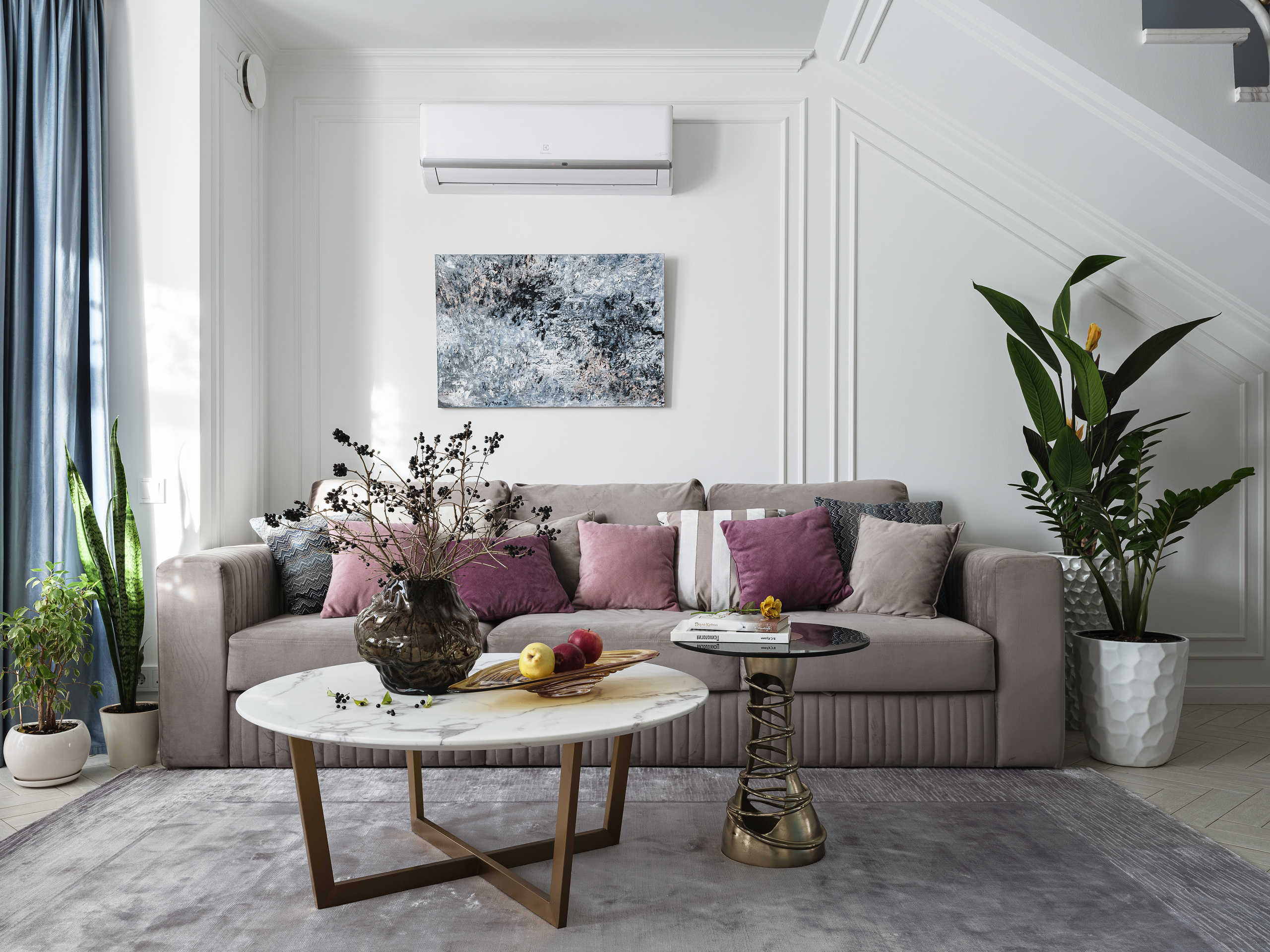 Светлая гостиная с серым диваном, декоративными подушками бордового и розового оттенка, мраморным круглым столиком и живыми растениями в горшках. Интерьер создан дизайнерами Светланой Олефиренко и Марией Морозовой, фото Сергея Денисенко.