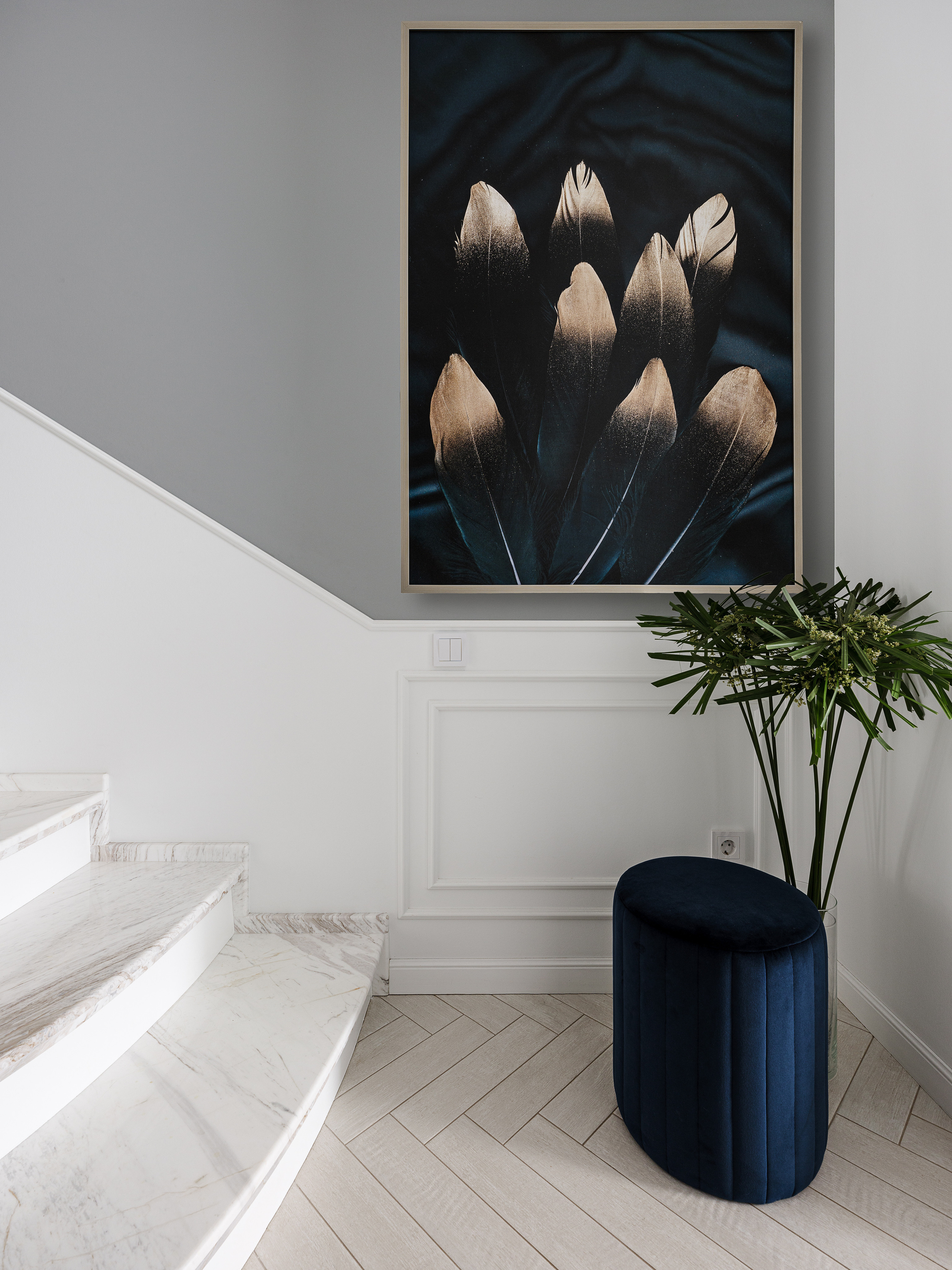 Элегантный интерьер лестничного холла с мраморными ступенями, картина с изображением золотистых перьев, темный пуф и живая зелень, дизайн Светланы Олефиренко и Марии Морозовой, фотограф Сергей Денисенко.
