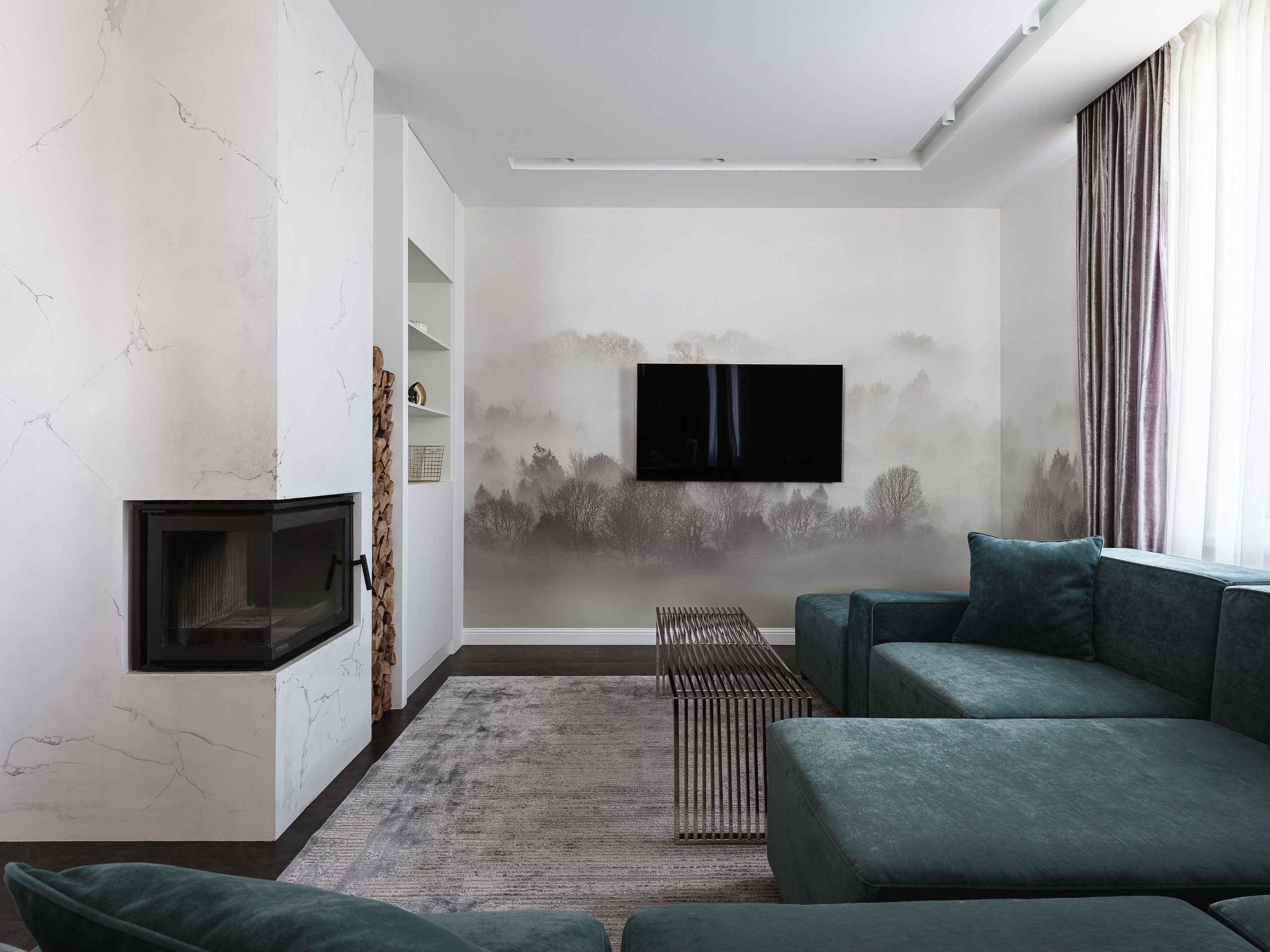 Интерьер гостиной с акцентной стеной с рисунком туманного леса, телевизором и стильным журнальным столиком, созданный дизайнером Ириной Вольхиной, стилистом Мариной Чернышевой и снятый фотографом Сергеем Денисенко для проекта.