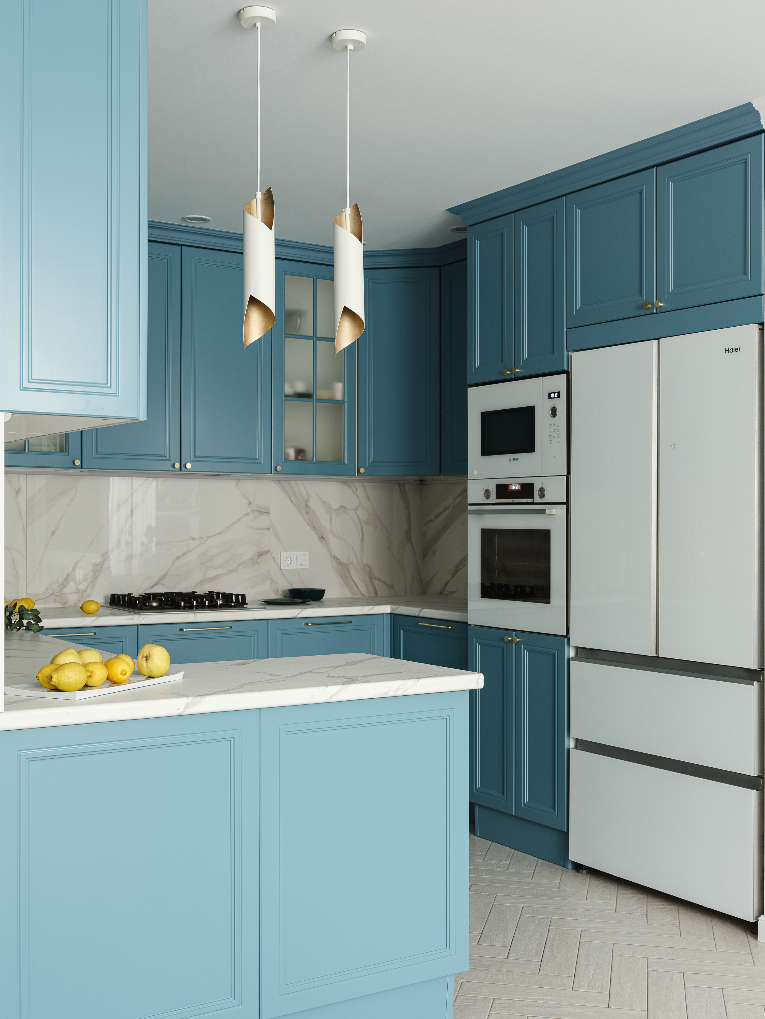 Интерьер кухни с голубыми шкафами, встроенной бытовой техникой, белым холодильником и мраморными поверхностями, проект Светланы Олефиренко и Марии Морозовой, фотосъёмка Сергея Денисенко, гармоничное сочетание цветов и фактур.