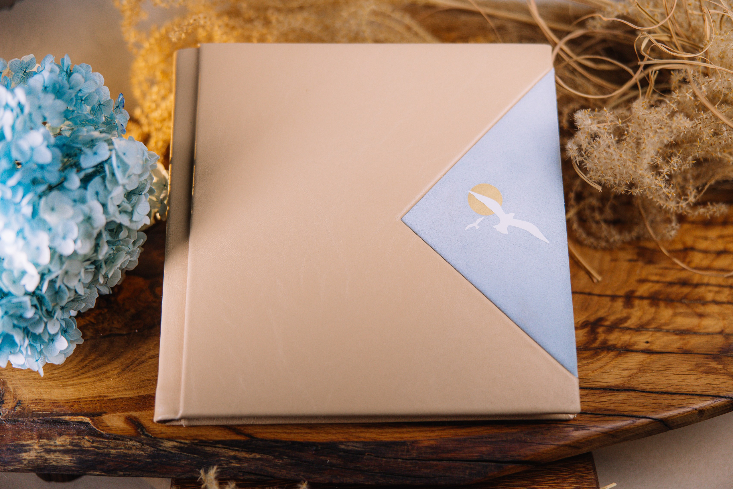 Дизайнерская фотокнига ручной работы с минималистичным рисунком птицы и солнца на фоне голубого неба