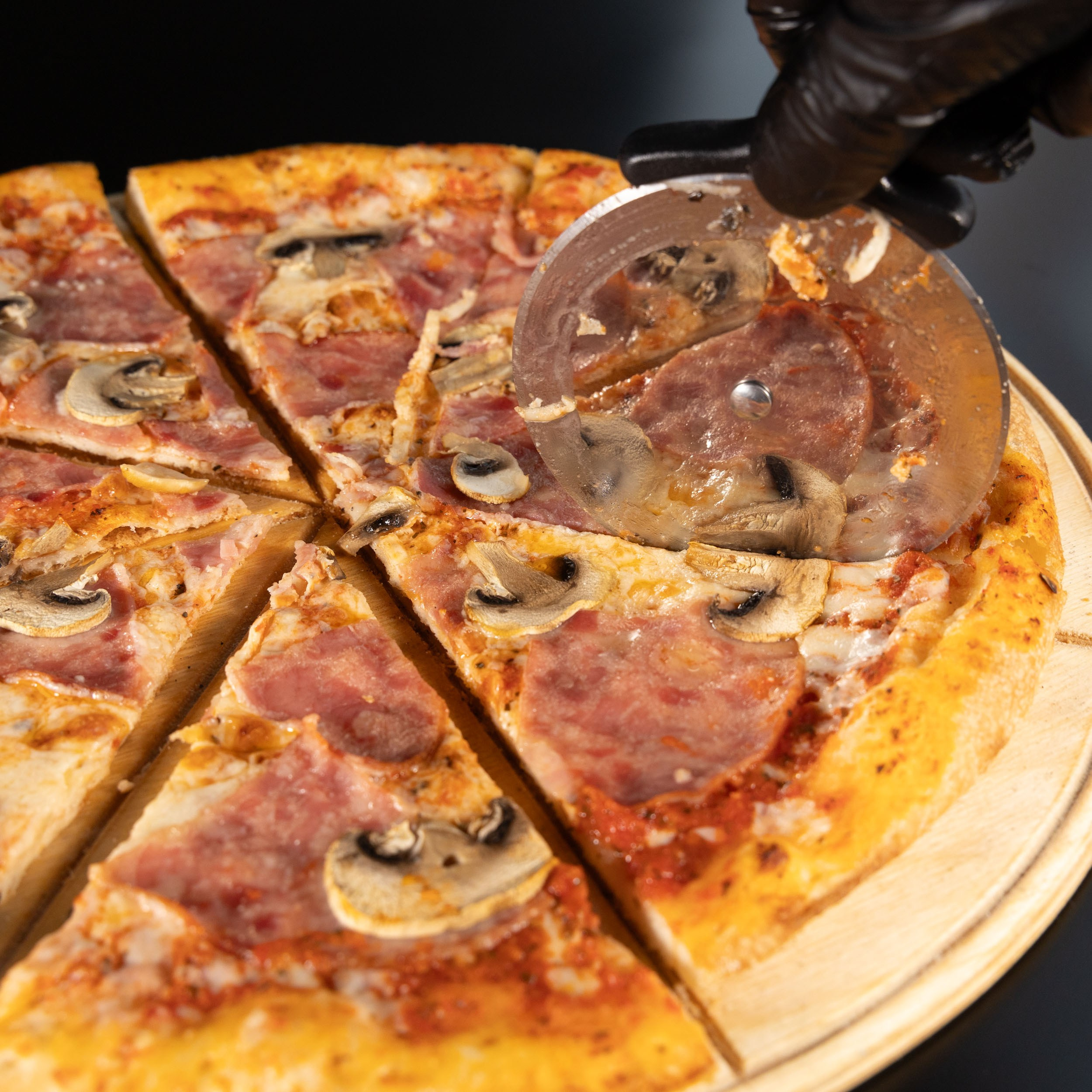 Разрезание пиццы круглым ножом.