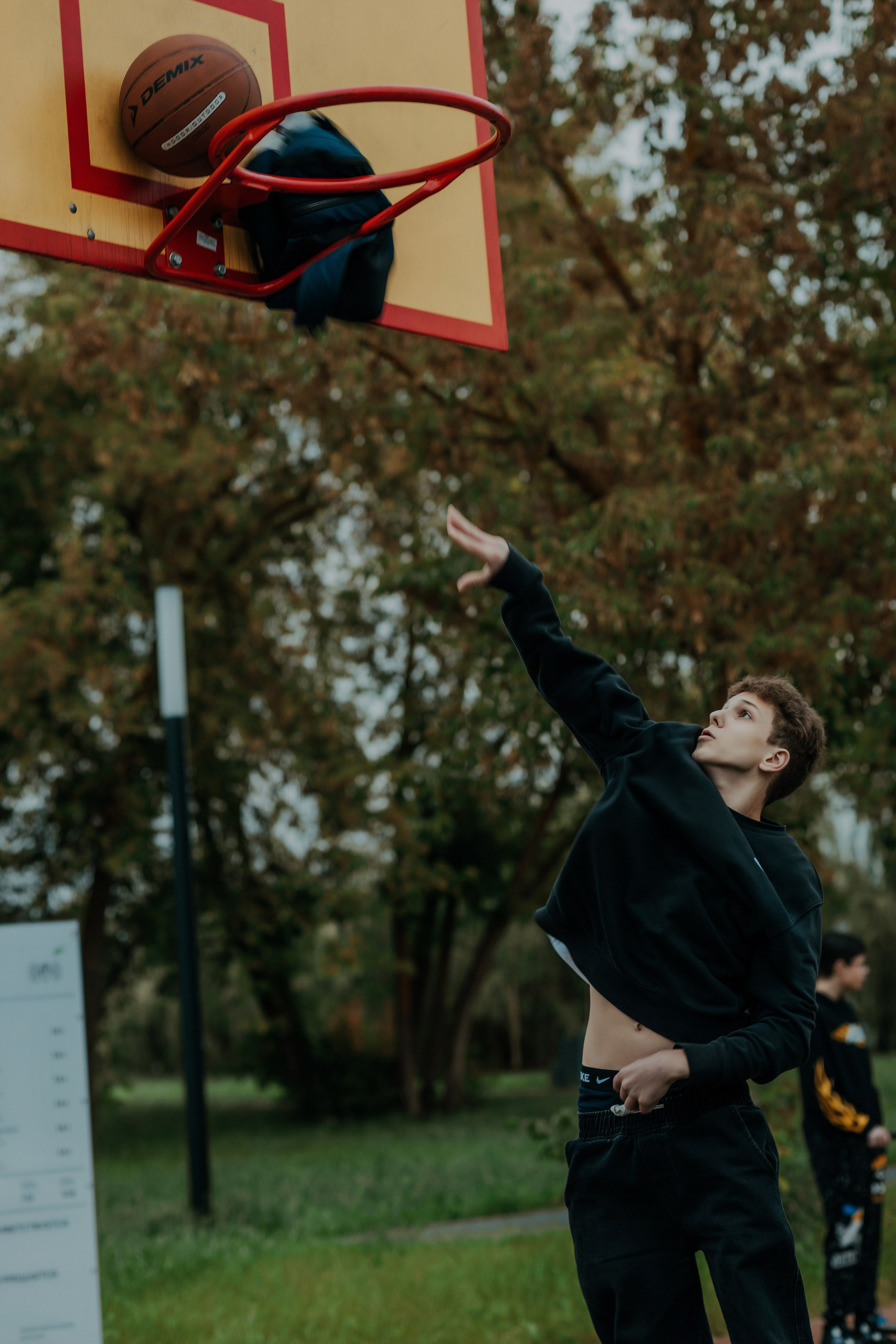 Школьник забрасывает мяч в корзину