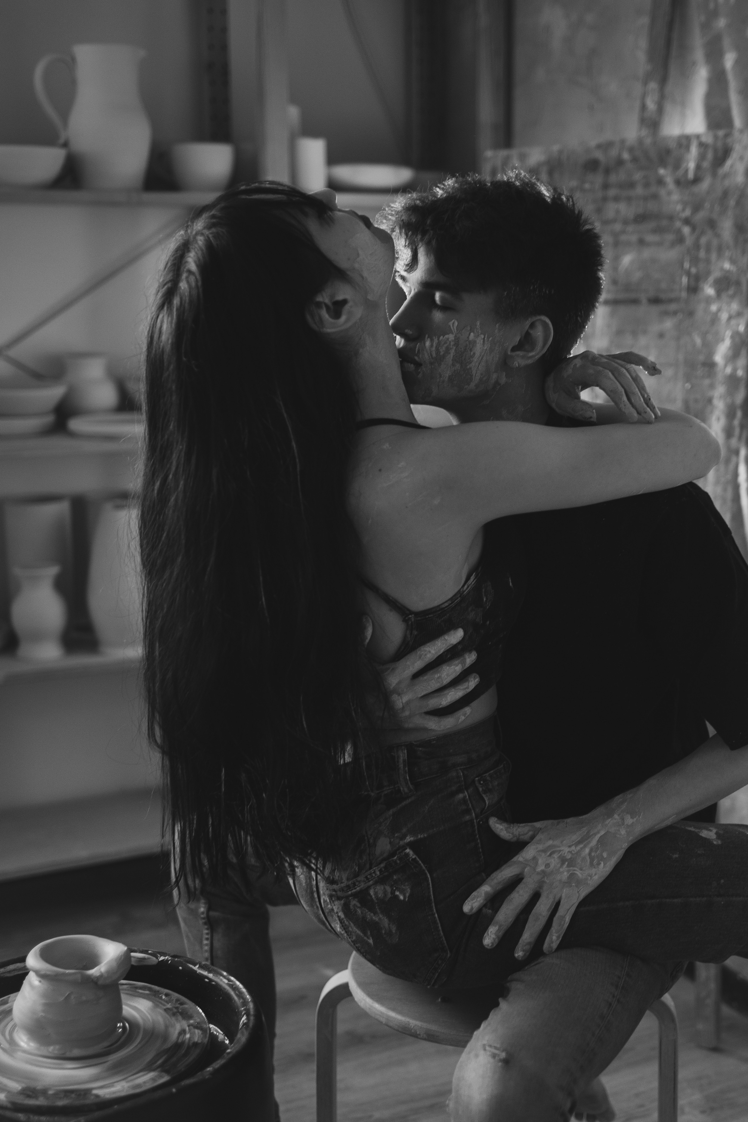 Лавстори в гончарной мастерской. Парень с девушкой сидят на стуле возле гончарного круга с глиной