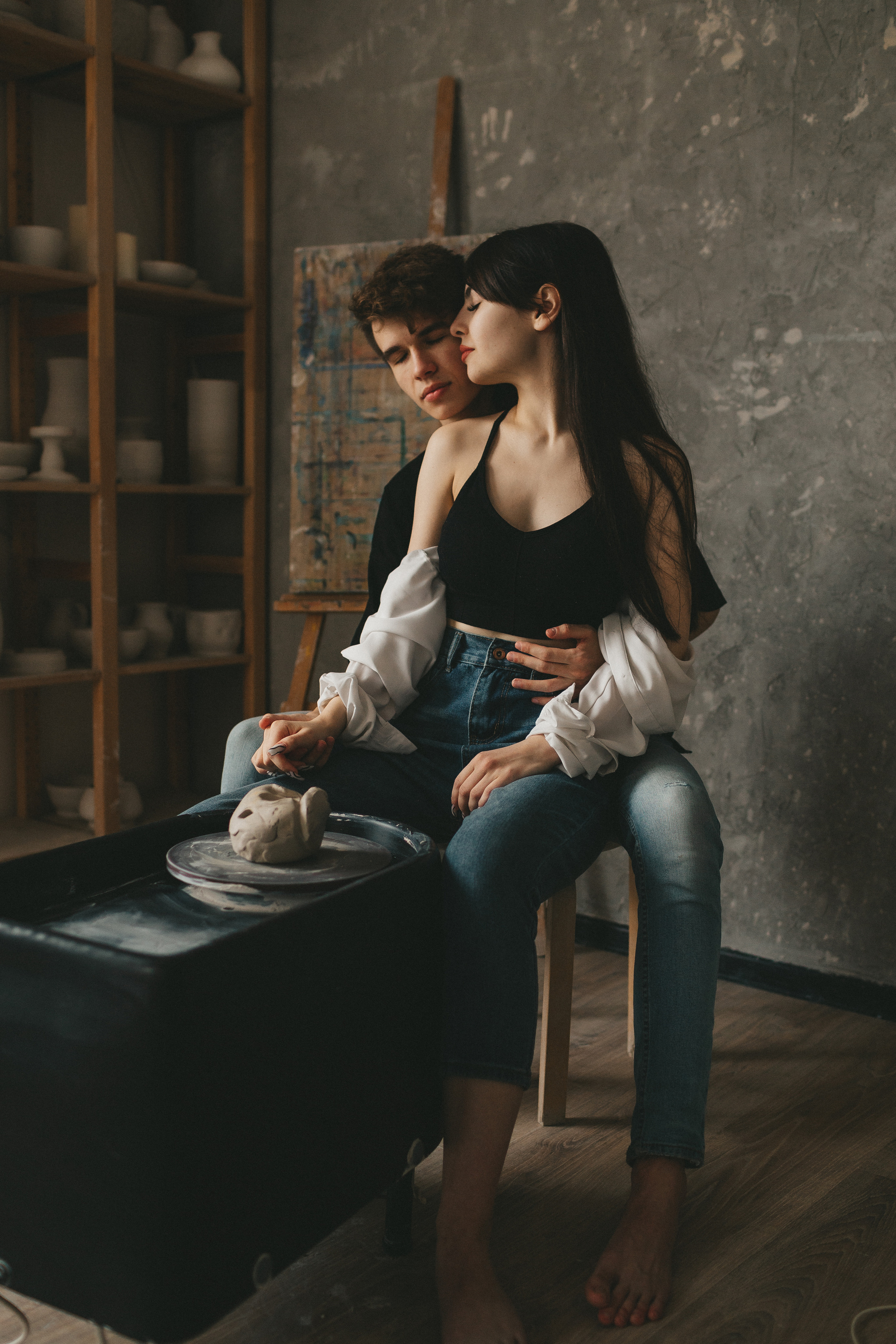 Лавстори в гончарной мастерской. Парень с девушкой сидят на стуле возле гончарного круга с глиной