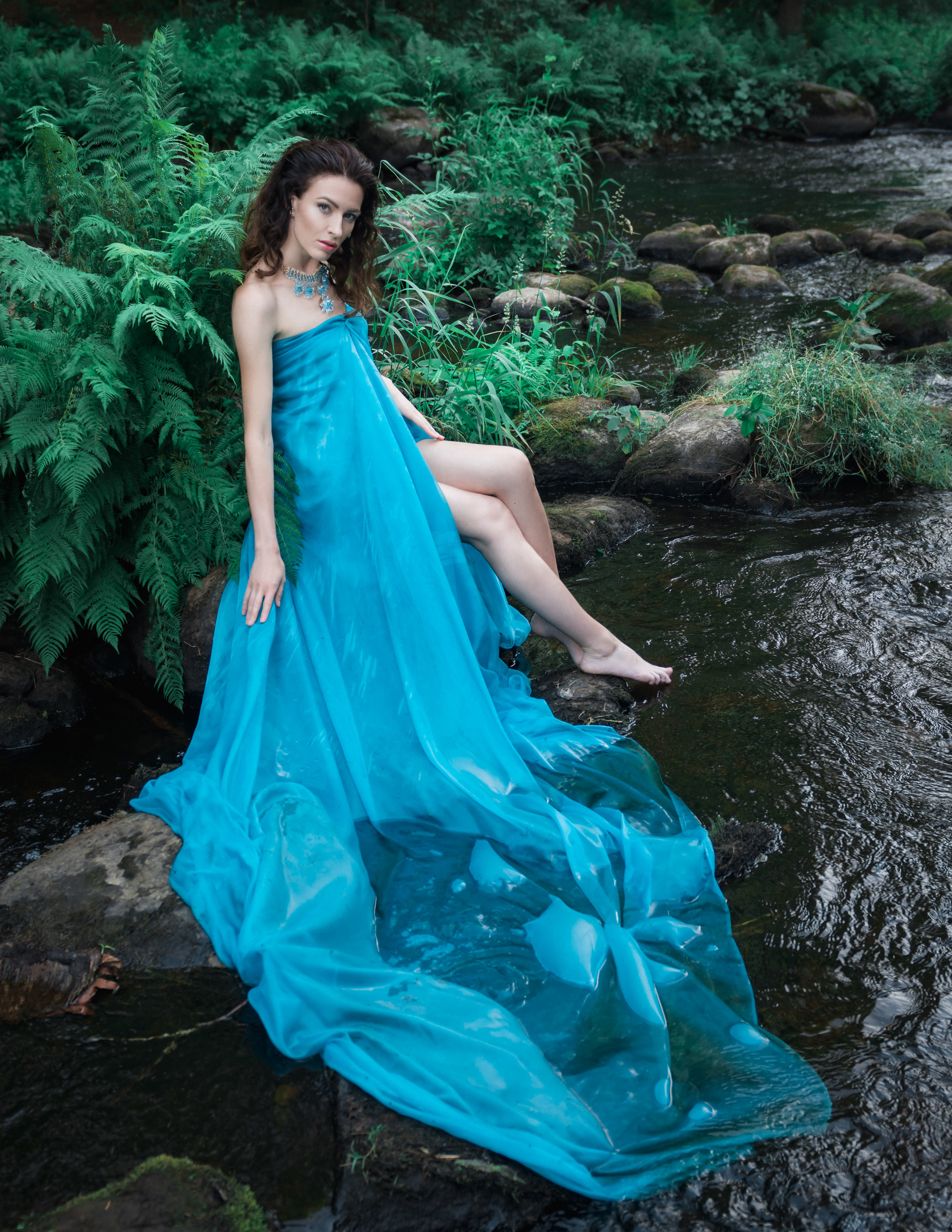 Девушка в голубом платье в реке, рядом папоротник