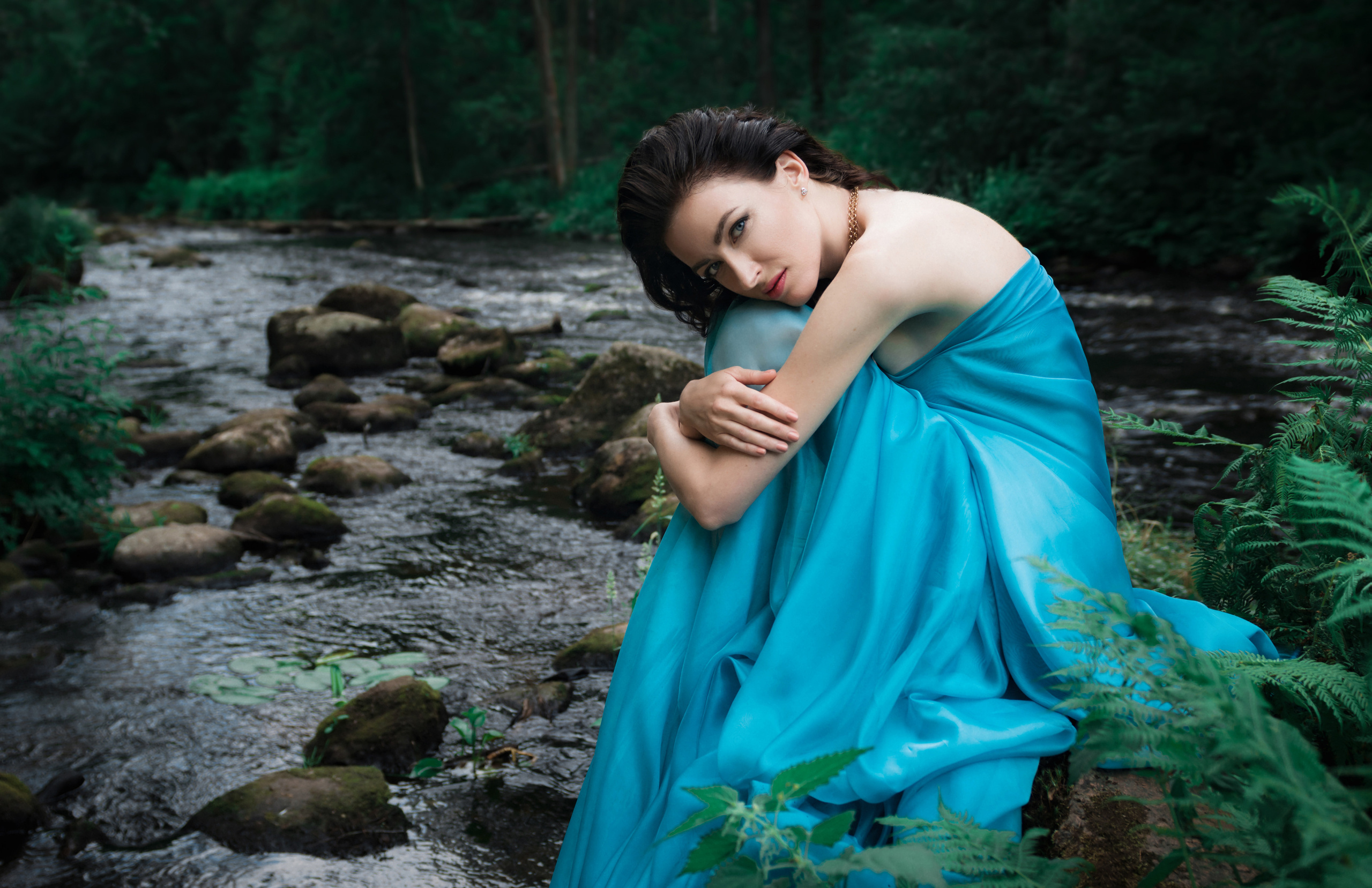 Девушка сидит на камнях на берегу реки