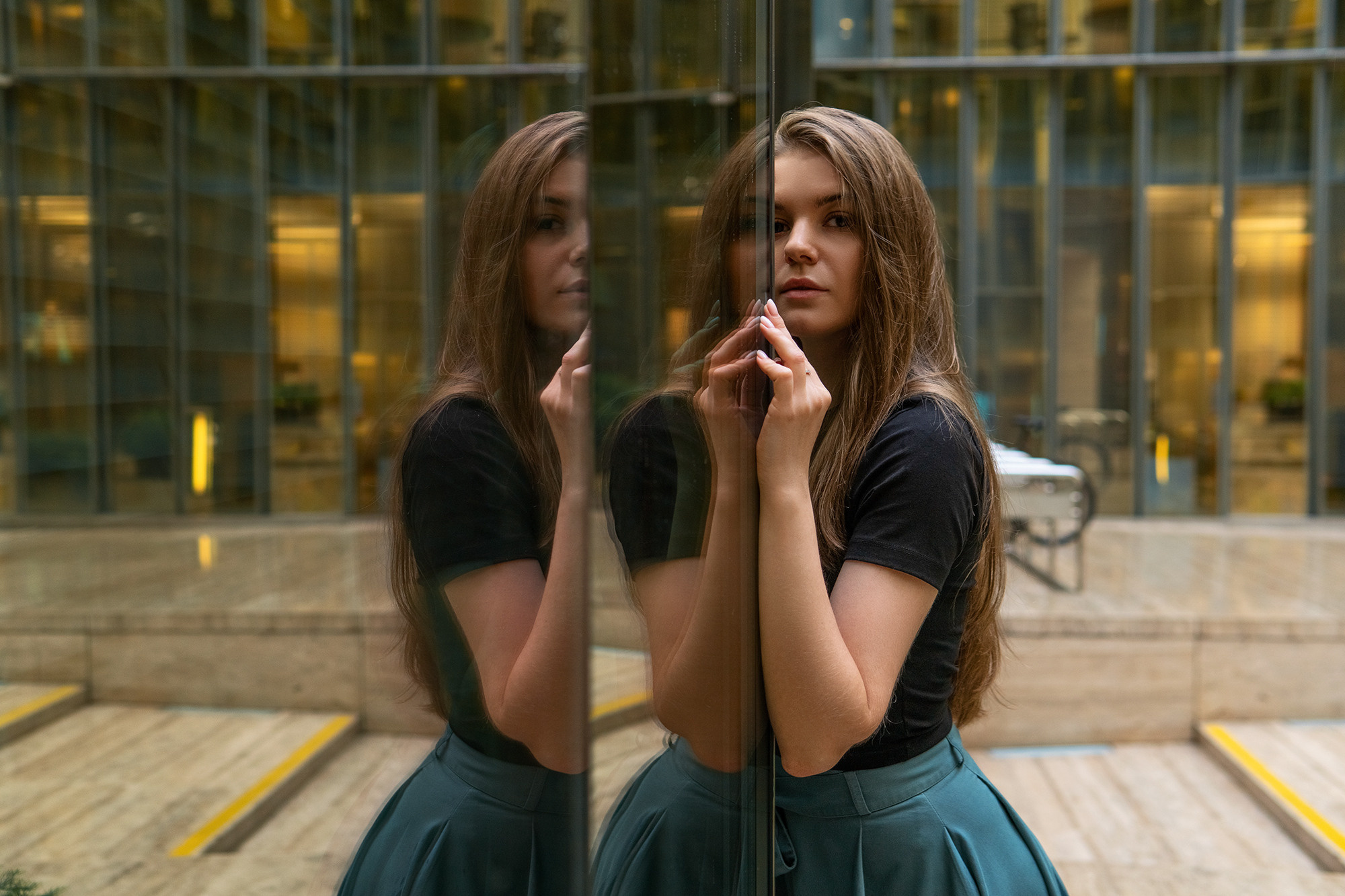 Девушка стоит у зеркальной стены, в котором видно ее отражение