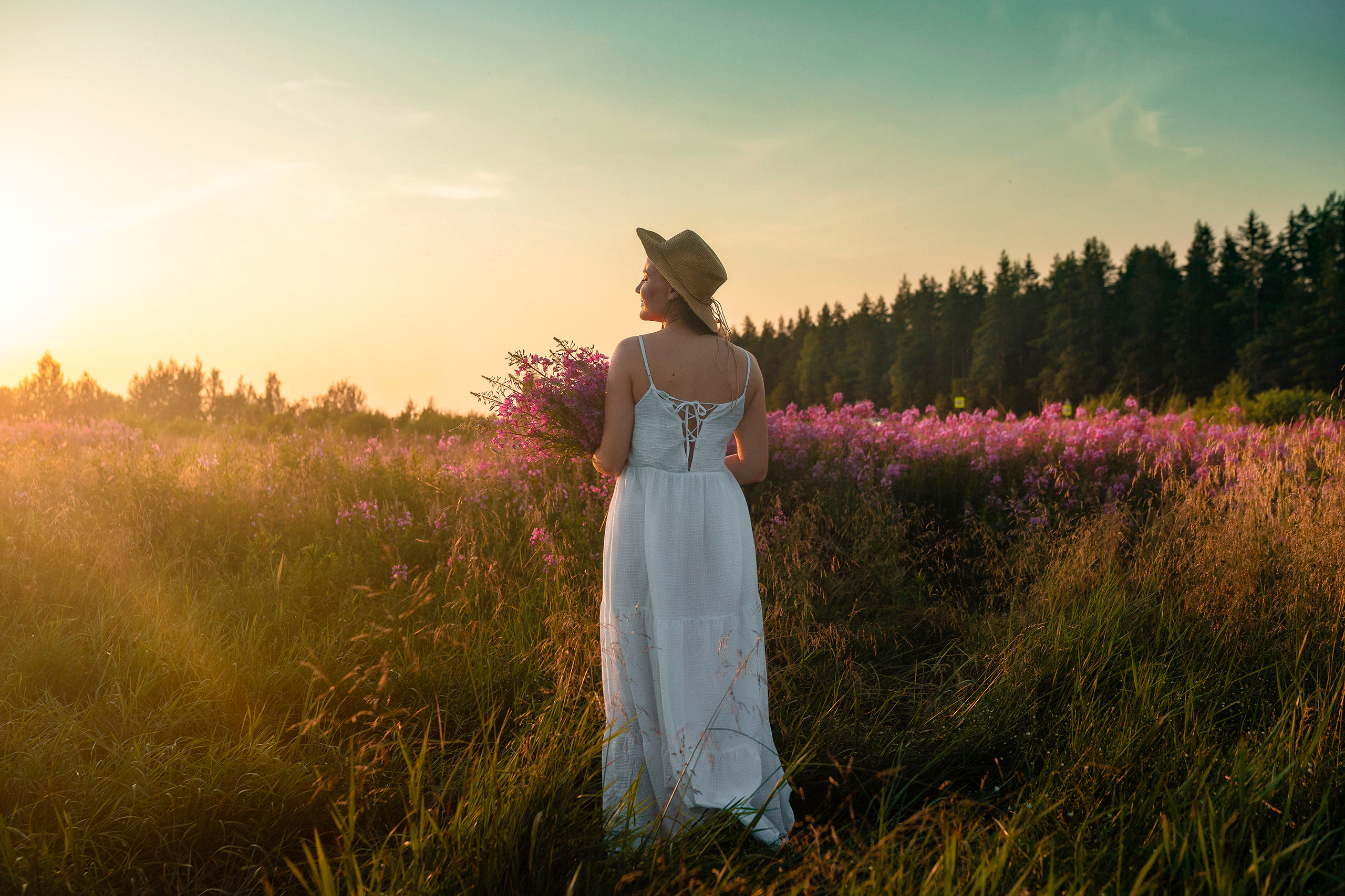 Девушка с цветами в руках на закате  в поле