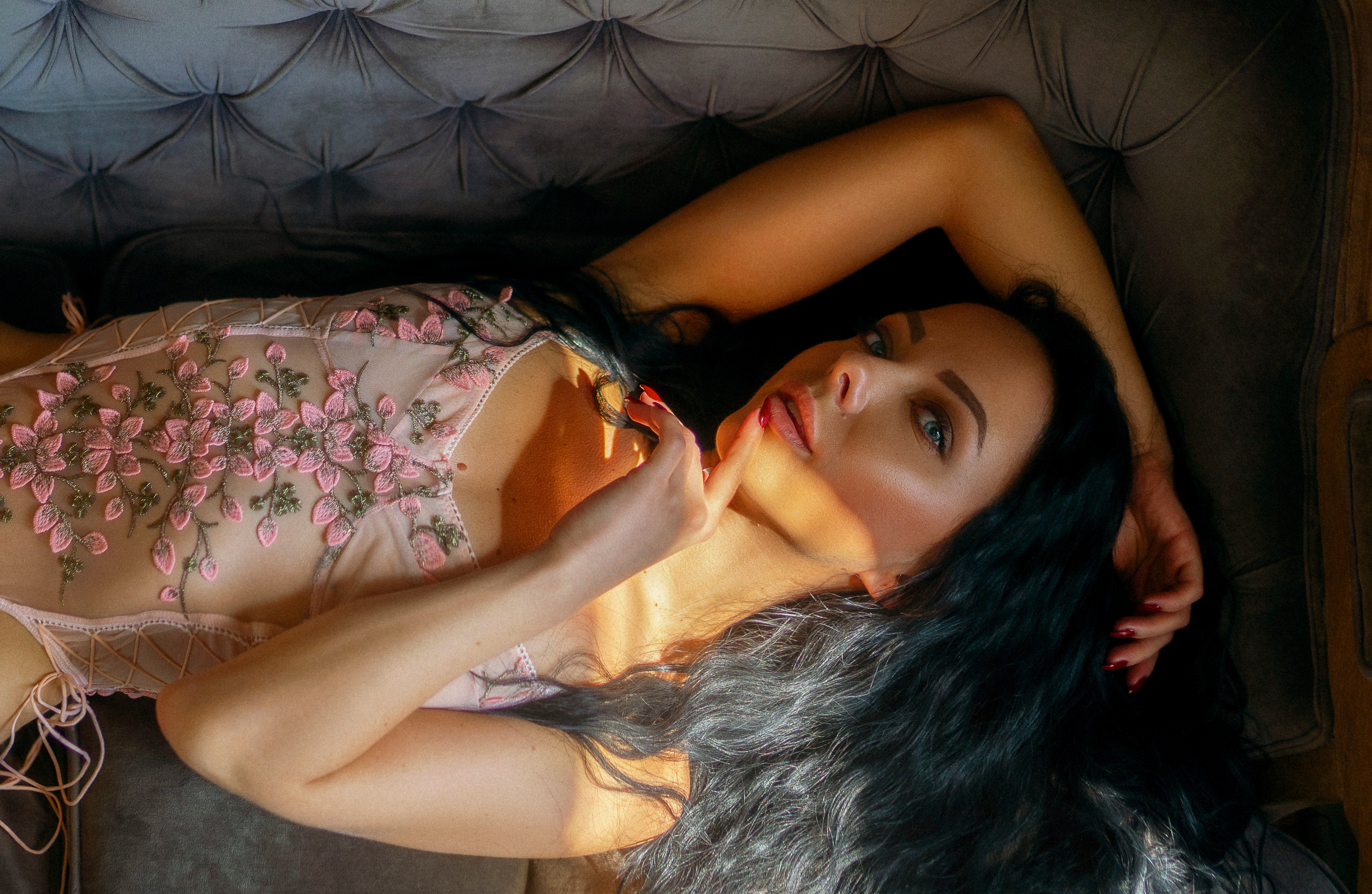 Девушка в боди лежит на диване старых веков и смотрит вверх