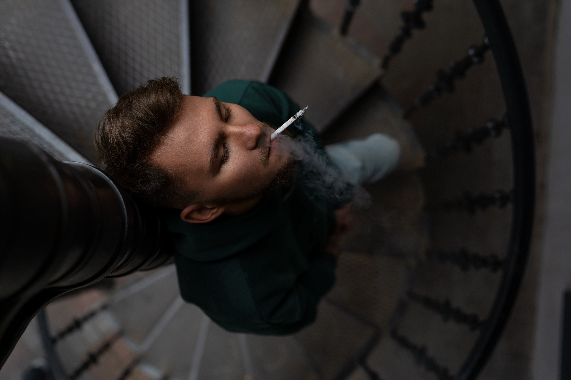 Парень курит на винтовой лестнице