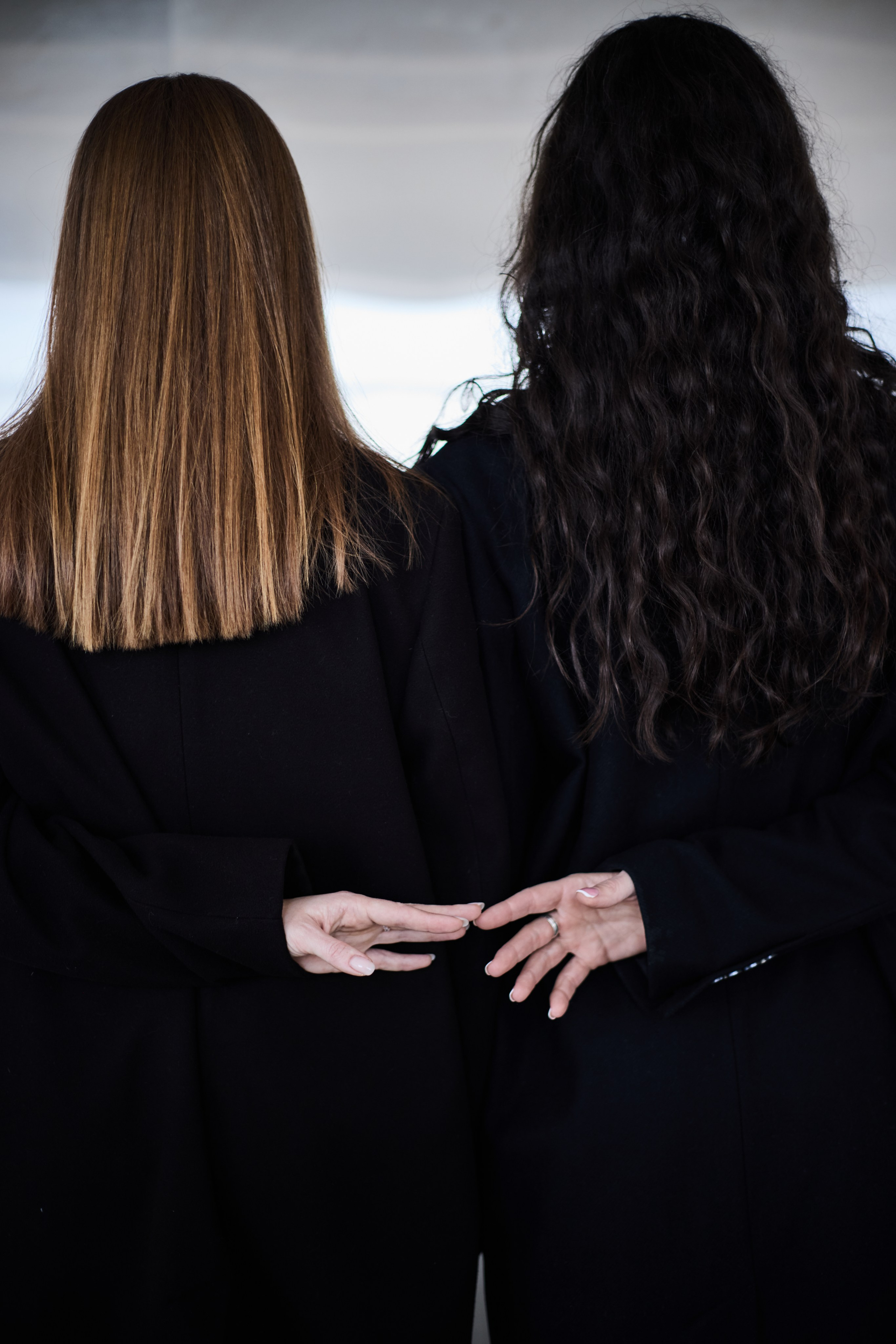 Две девушки на фоне металлической стены, стоят спиной, взявшись за руки. Виктория Брызгалова и Анна Пижонкова