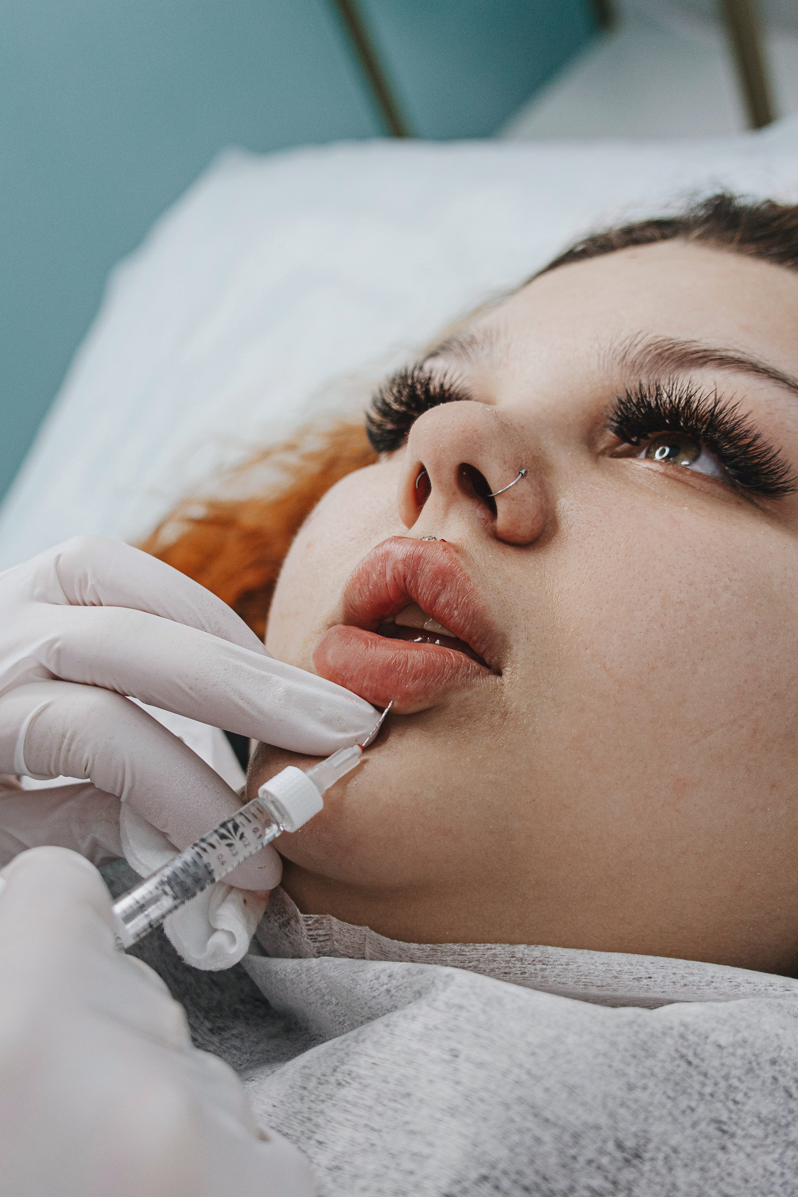 Косметолог делает инъекцию в губы пациентке, крупный план шприца и губ