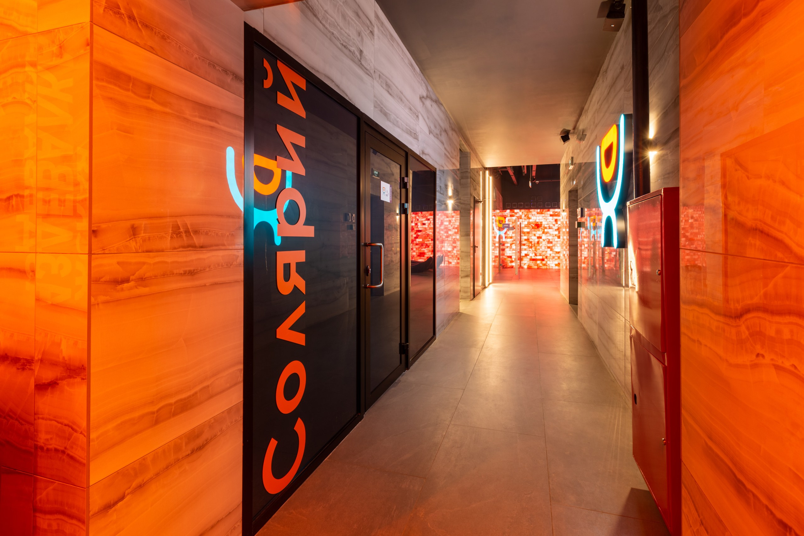 Фото в оранжевых тонах. Большая надпись солярий на стене. Солярий в тренажёрном зале. Солярий в зале премиум класса.