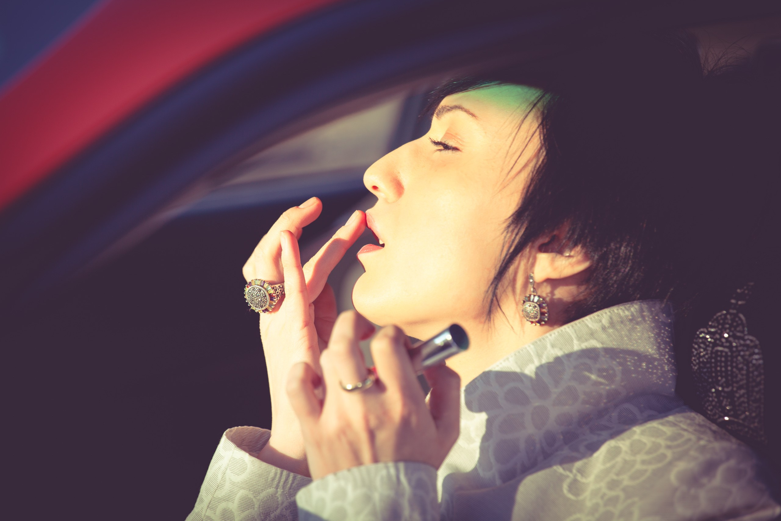 Девушка в элегантном пальто сидит за рулем современного автомобиля, сочетая классический стиль и динамичную жизнь.