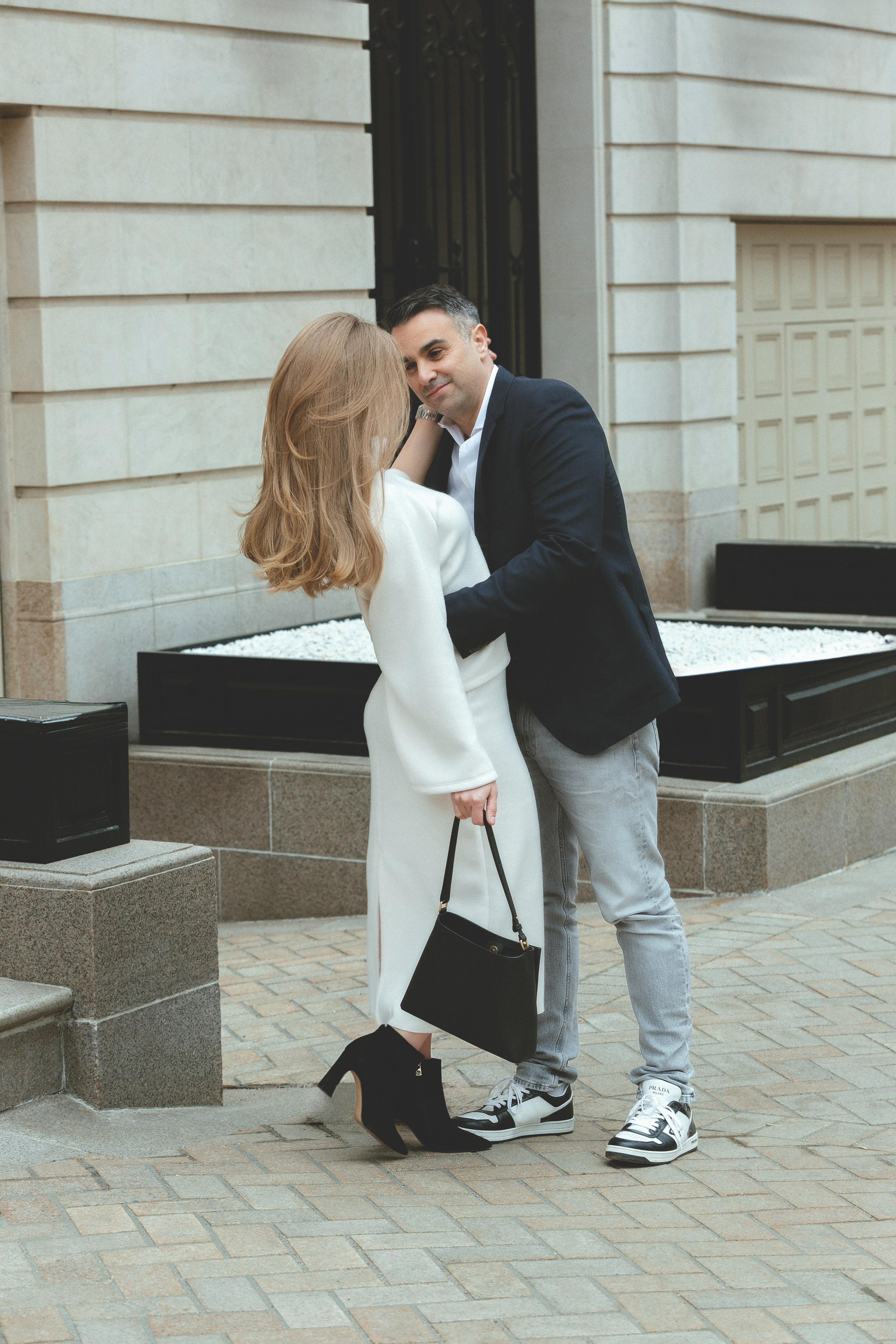 Влюблённые смотрят друг на друга на фоне фасада — фотосессия пары в минималистичном архитектурном окружении