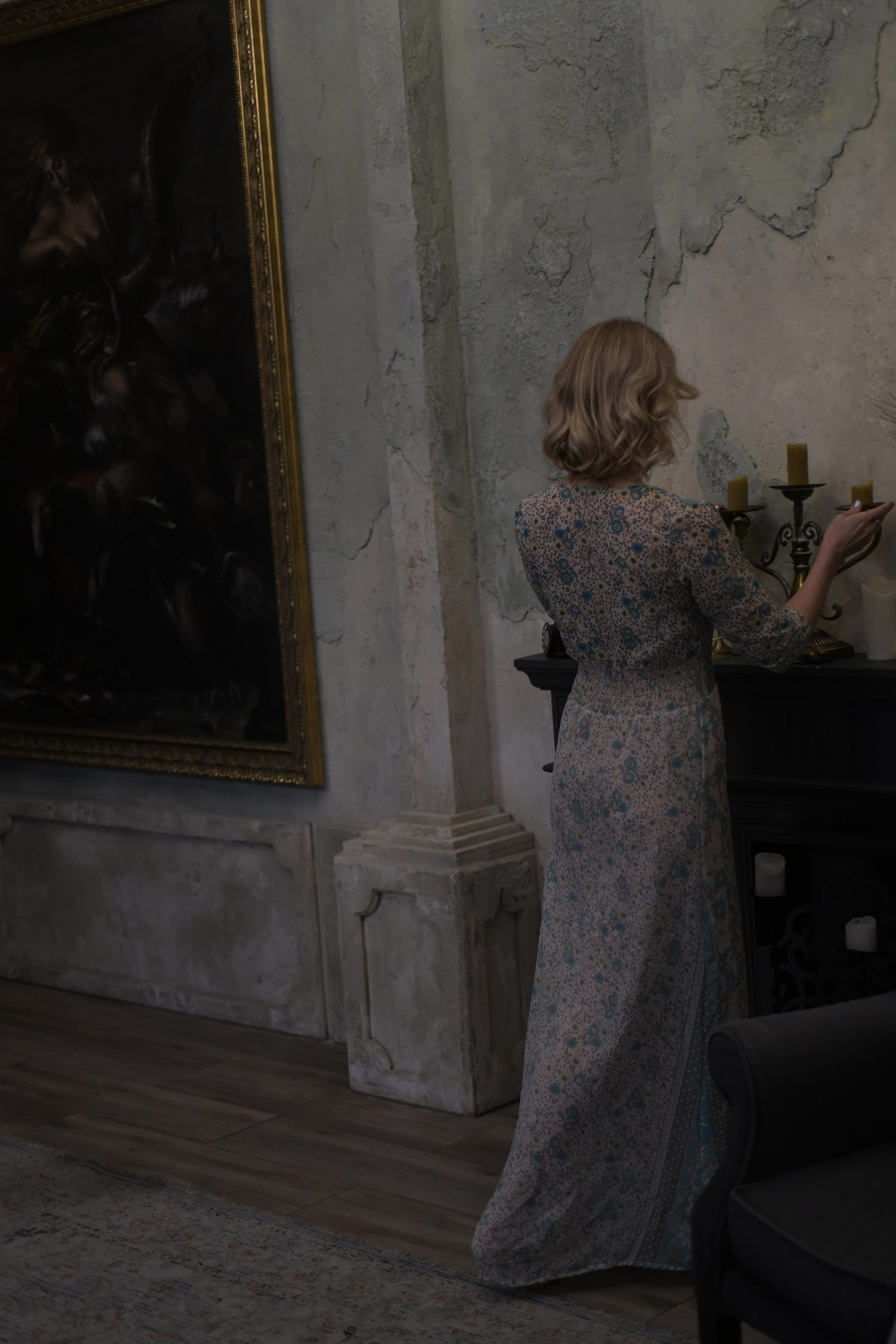 Девушка в красивом платье украшает интерьер комнаты.