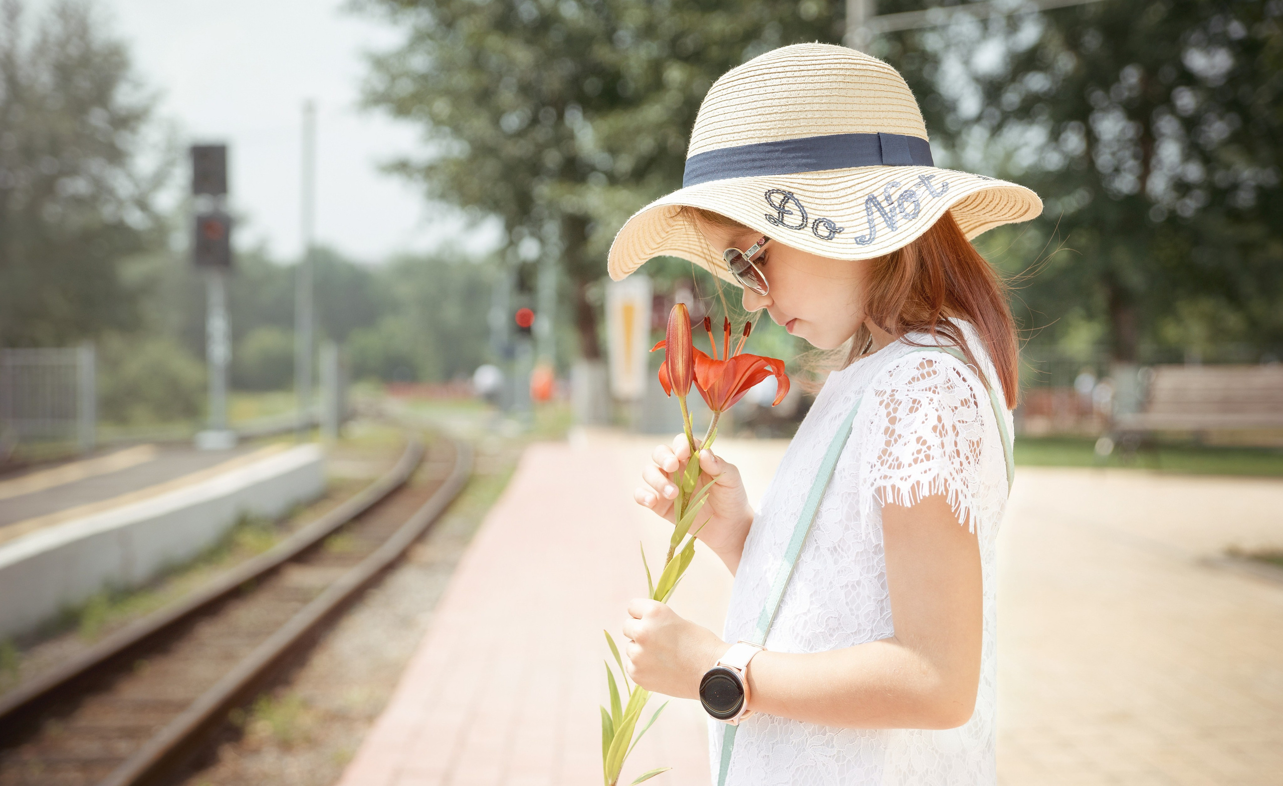 Детская фотосессия летом - девочка стоя смотрит на цветы