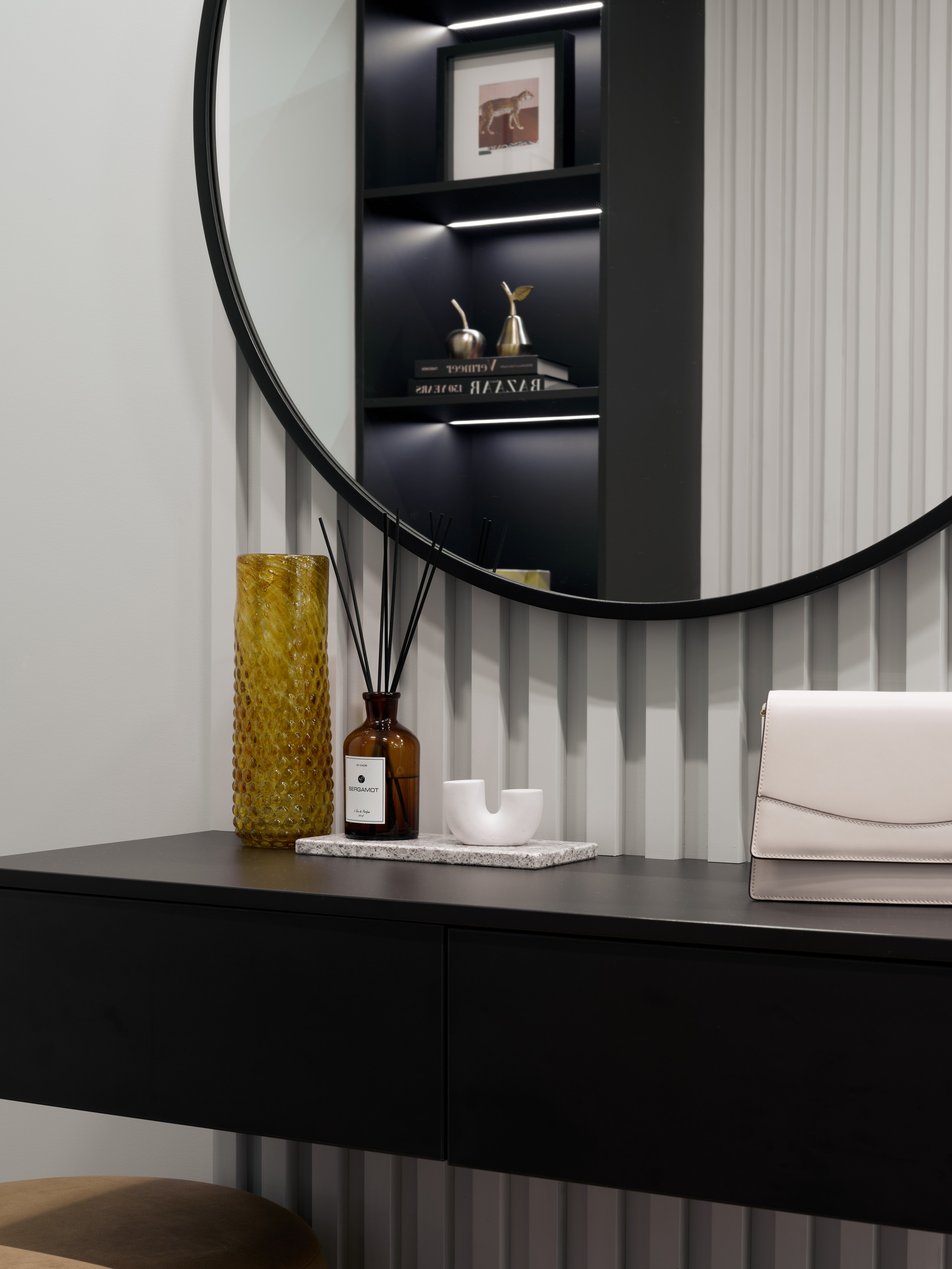 Туалетный столик с круглым зеркалом, декоративными аксессуарами и контрастными деталями, интерьер квартиры от дизайнера Екатерины Мищенко, фото Сергея Денисенко, современная эстетика с акцентом на минимализм и функциональность.