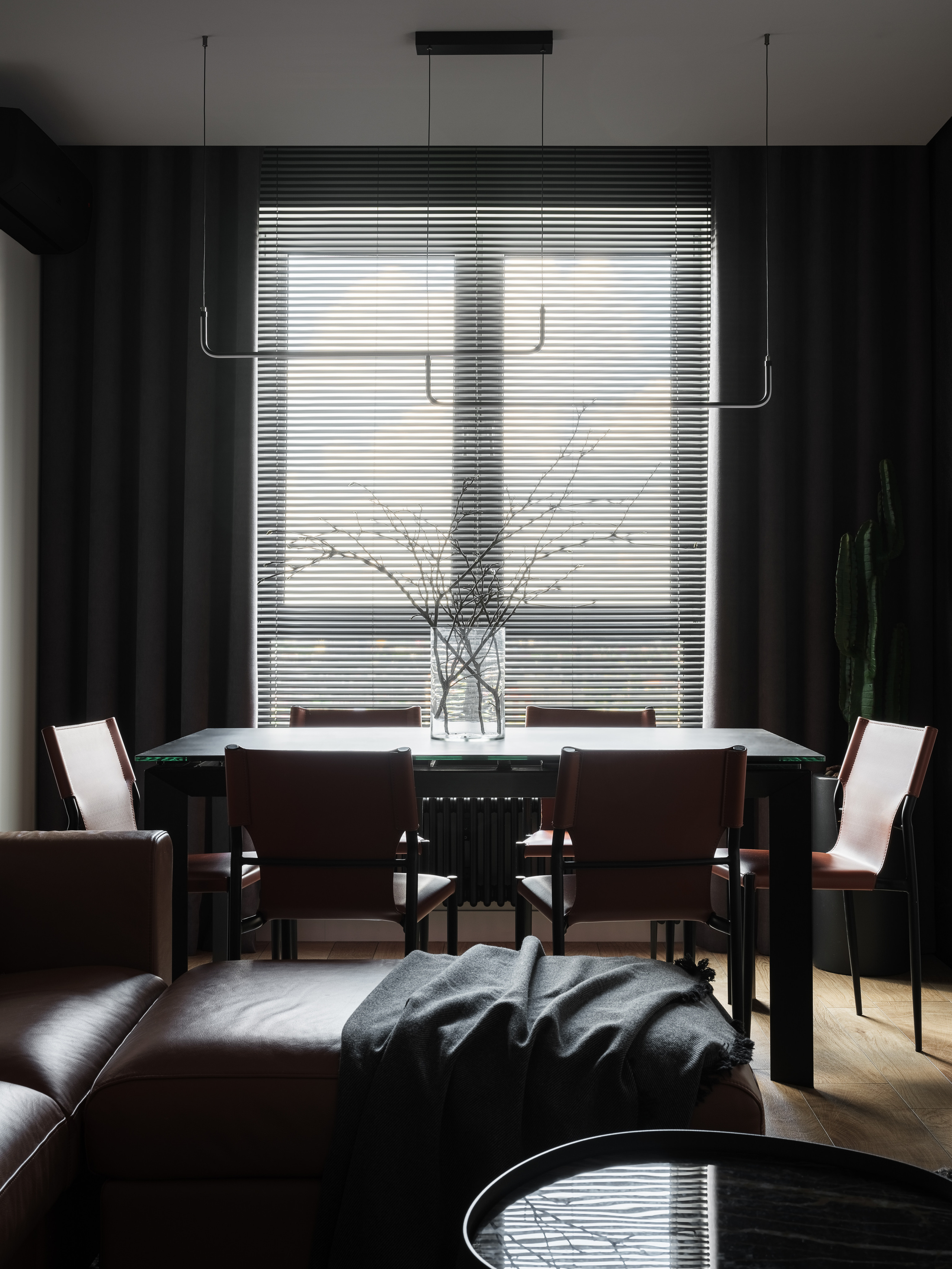 Современная столовая с большим окном и жалюзи, чёрным столом, кожаными стульями и стеклянной вазой с ветками, уютная атмосфера в минималистичном стиле, дизайн Алёна Сверлова, фотосъёмка Сергей Денисенко.