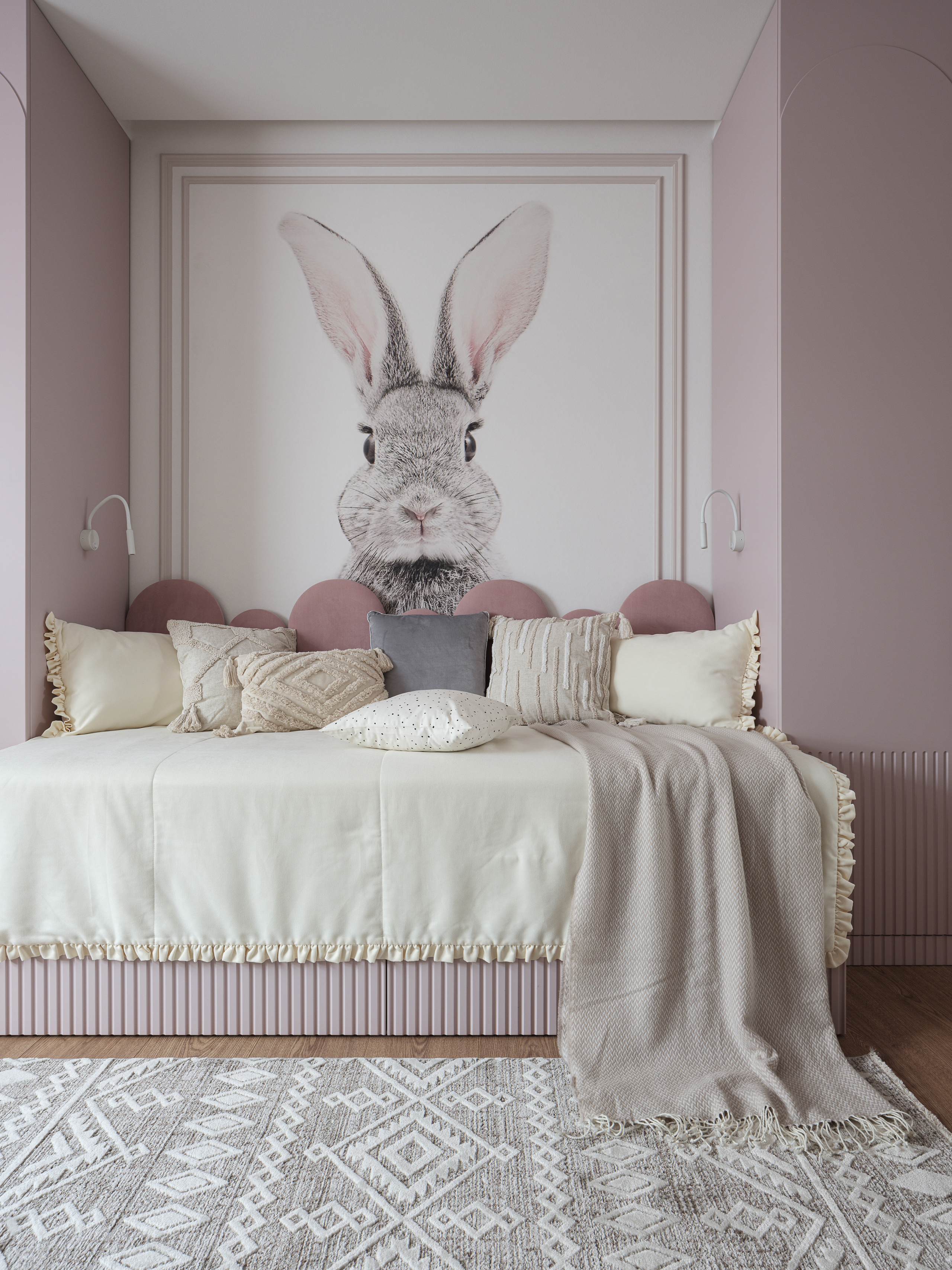 Интерьер детской комнаты с акцентной стеной и постером кролика, мягкая кровать с декоративными подушками и текстилем в пастельных оттенках. Дизайн Алёны Сверловой, фотография Сергея Денисенко, уют и стиль.