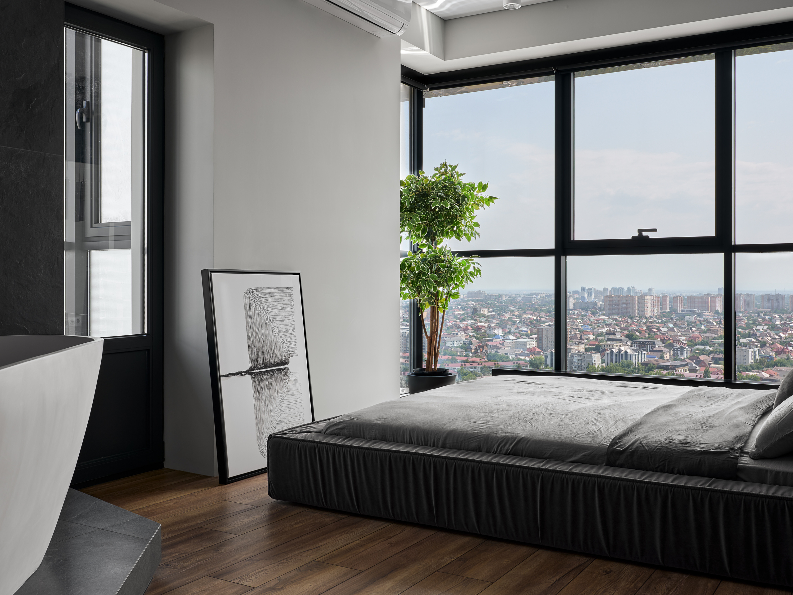 Современная спальня с панорамными окнами и видом на город, минималистичным чёрно-серым текстилем, графикой и зелёным растением в интерьере от дизайнеров Андрея Неленя и Екатерины Проскуряковой, стилистика Алины Нелень, фото Сергея Денисенко.