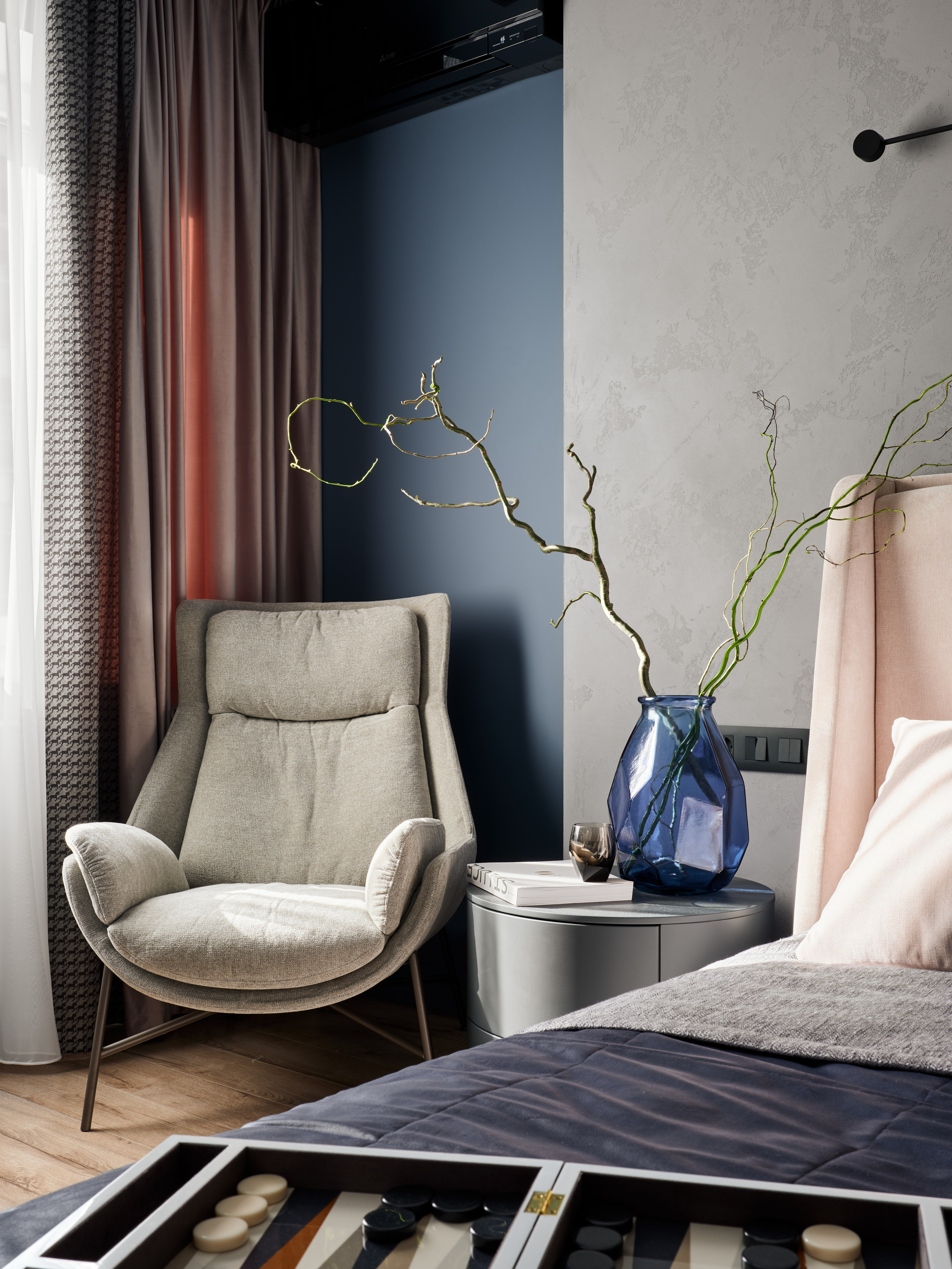 Стильное серое кресло у окна в спальне, дополненное шторой сложной фактуры и декоративной вазой с ветвями на тумбе. Декор и уютная атмосфера созданы дизайнером Екатериной Мищенко, фото Сергея Денисенко.