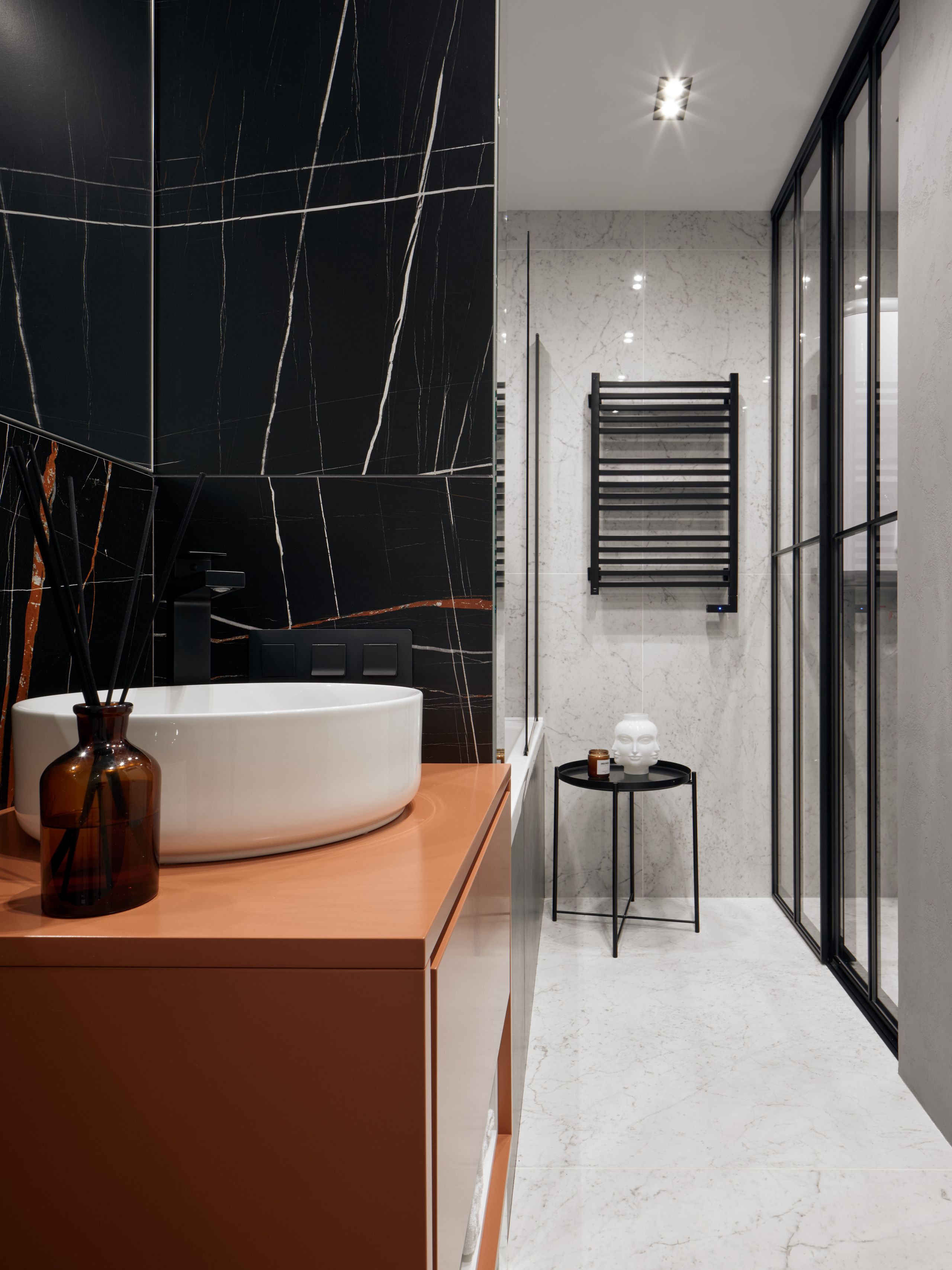 Интерьер ванной комнаты с круглой раковиной на тумбе терракотового оттенка и черной мраморной плиткой с прожилками, дизайнер Екатерина Мищенко, фотограф Сергей Денисенко, гармоничное сочетание цвета и фактур в современном стиле.