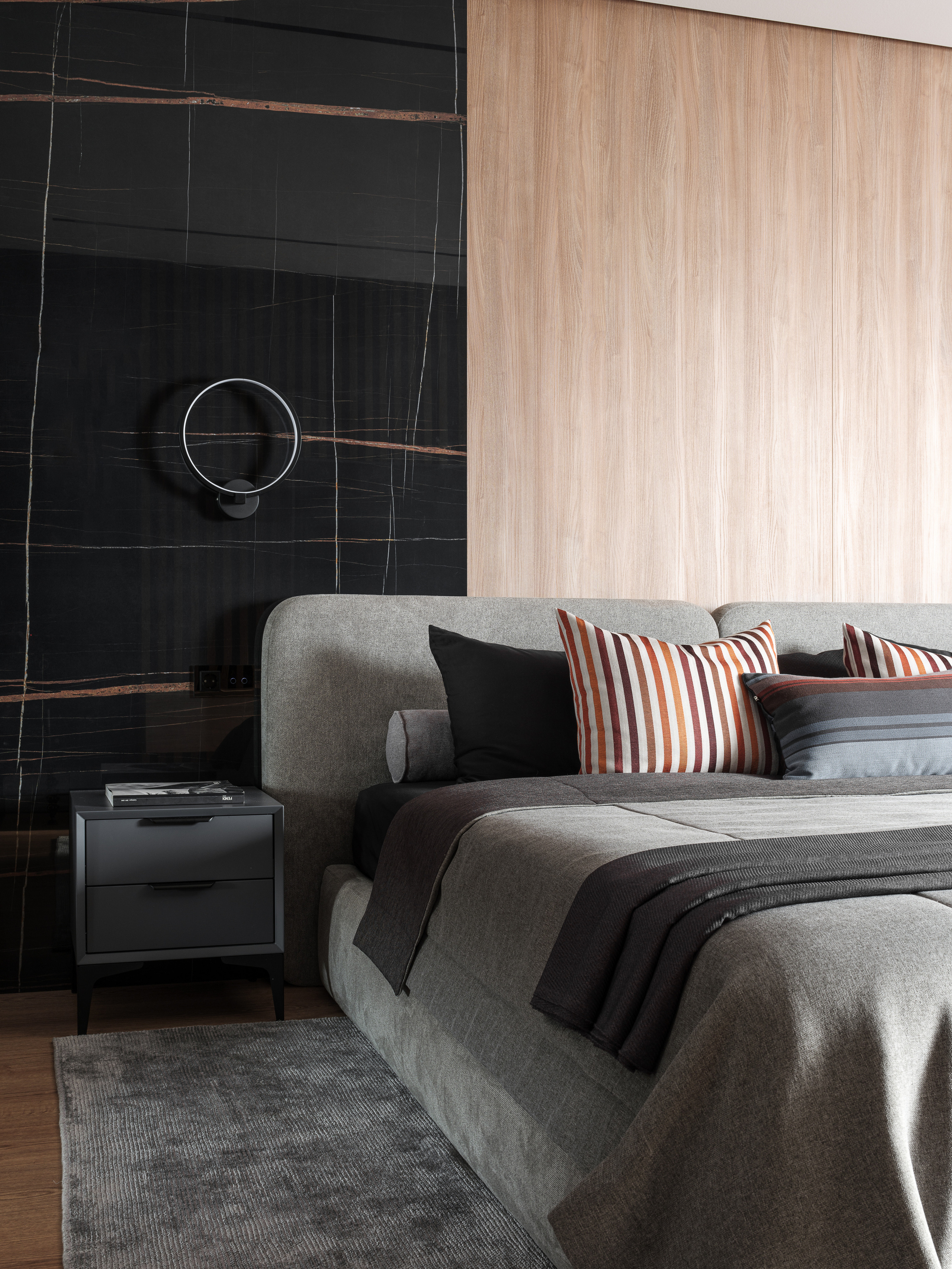 Современный интерьер спальни с черной акцентной стеной, серым текстилем на кровати и прикроватной тумбой в графитовом оттенке. Автор проекта Алёна Сверлова, фотограф Сергей Денисенко.