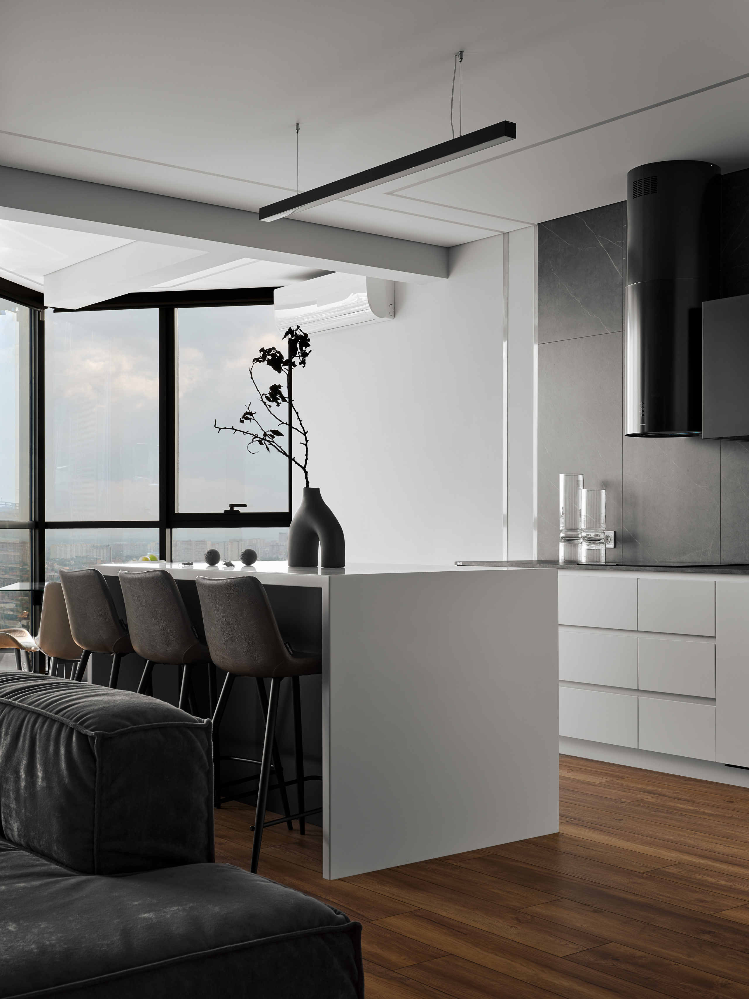 Элегантная кухня в современном стиле с белой барной стойкой, серыми стульями и панорамным окном с видом на город. Дизайнеры Андрей Нелень и Екатерина Проскурякова, стилист Алина Нелень, фотограф Сергей Денисенко.