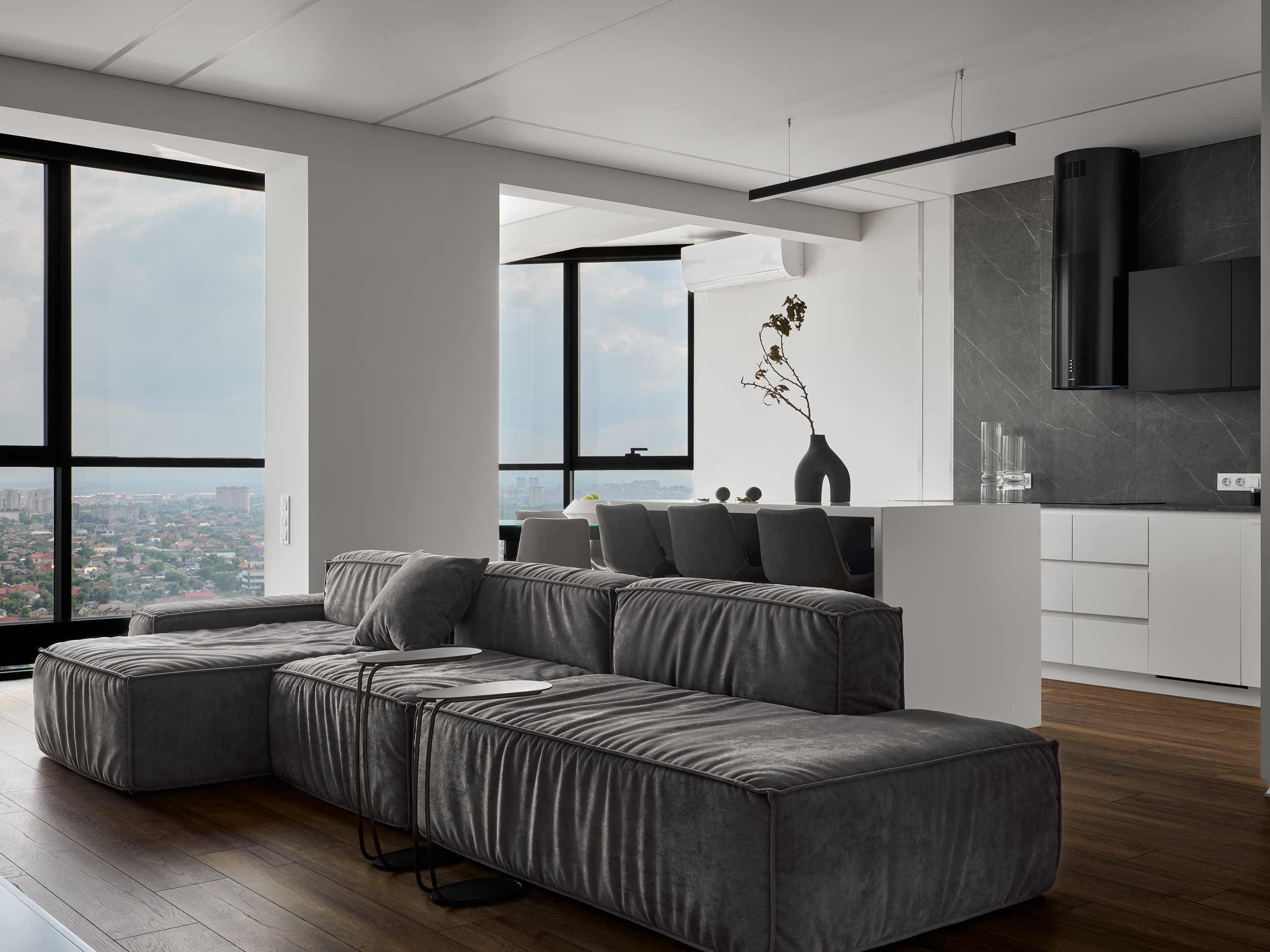 Просторная гостиная с мягким серым диваном, панорамными окнами и открытой кухней с белыми фасадами и графитовым фартуком. Интерьер от Андрея Неленя и Екатерины Проскуряковой, стилистика Алины Нелень, фото Сергея Денисенко.