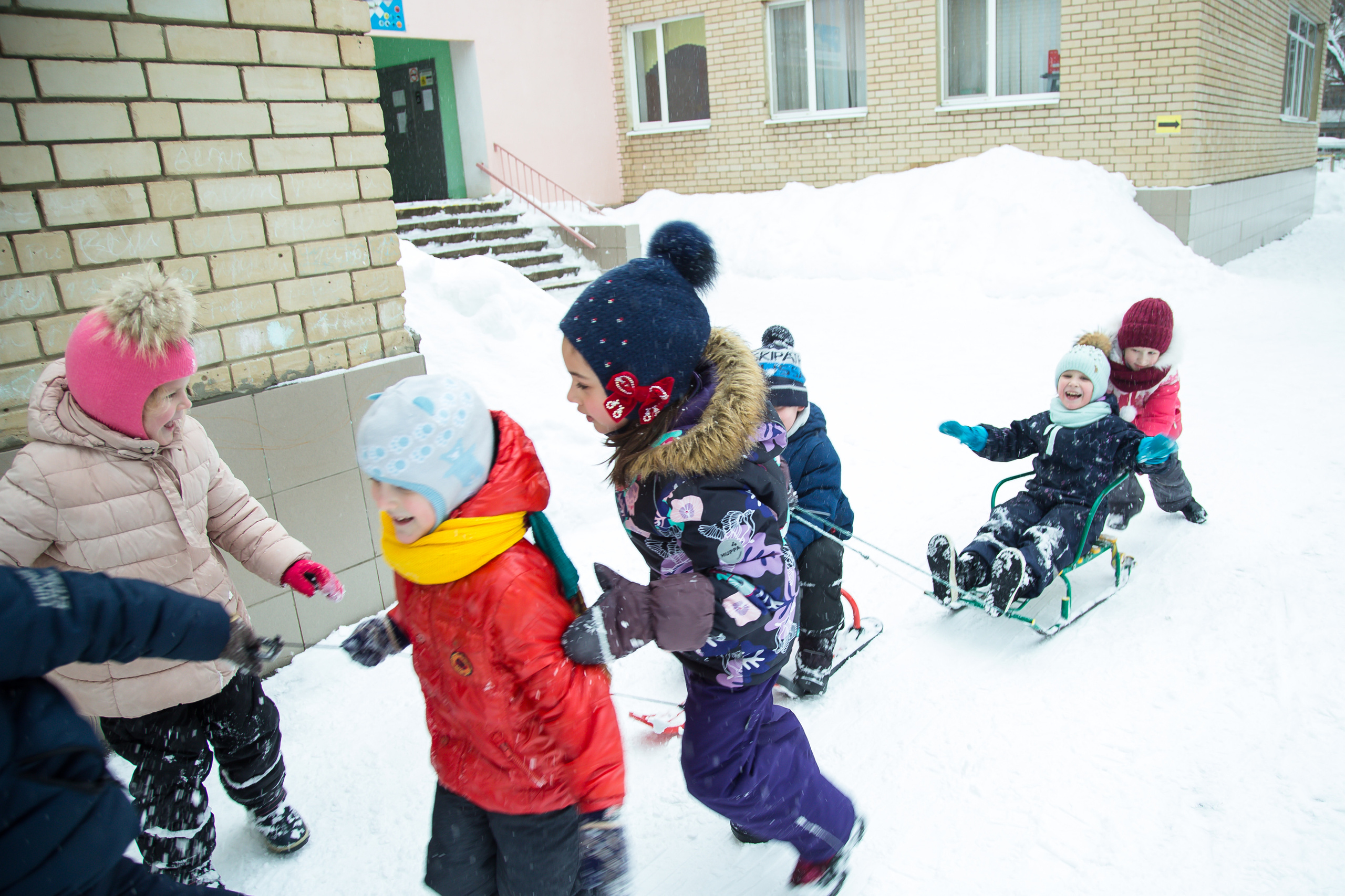 дети катаются на санках по снеггу