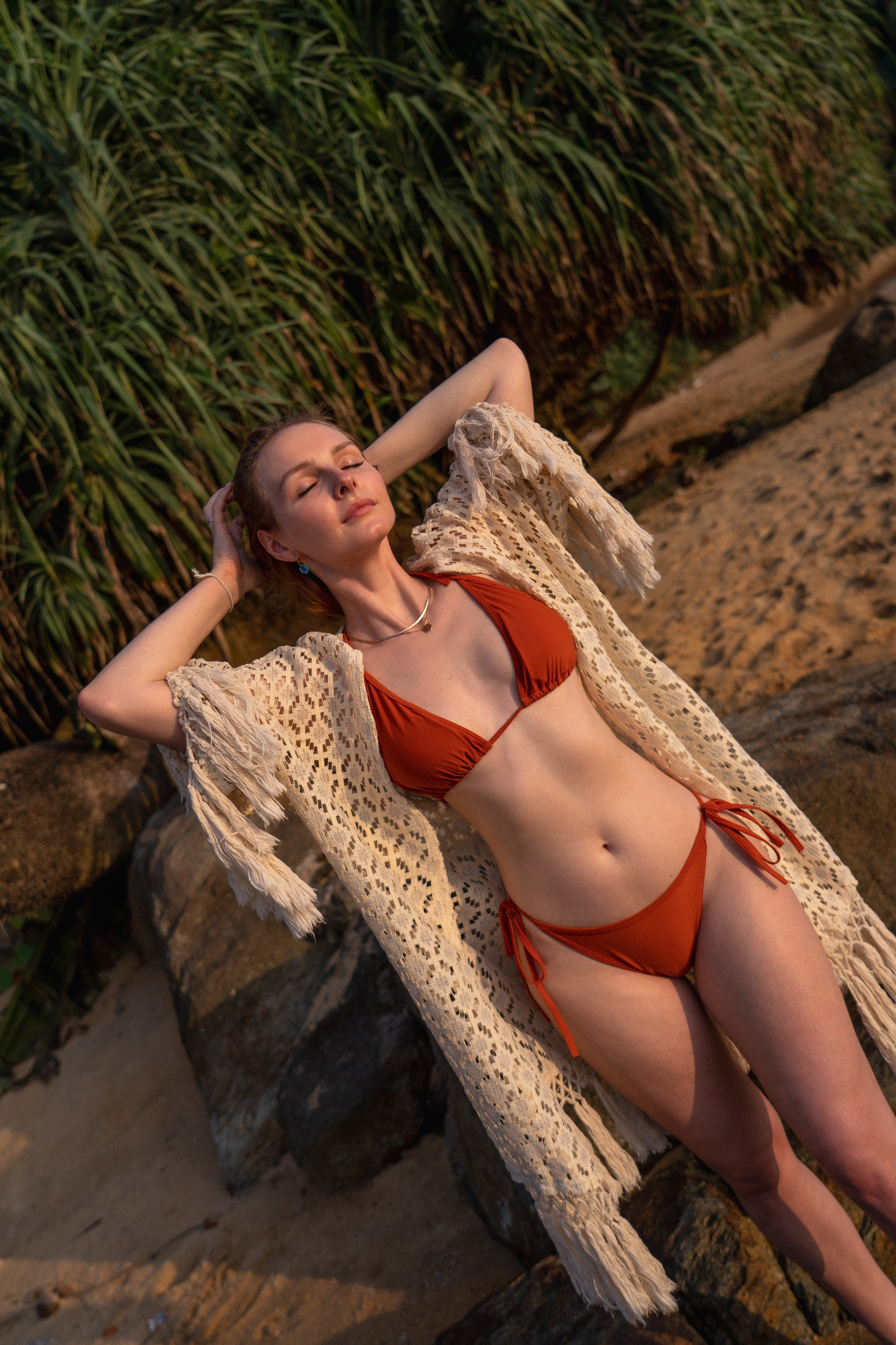 a girl in a red swimsuit posing on the beach at sunset