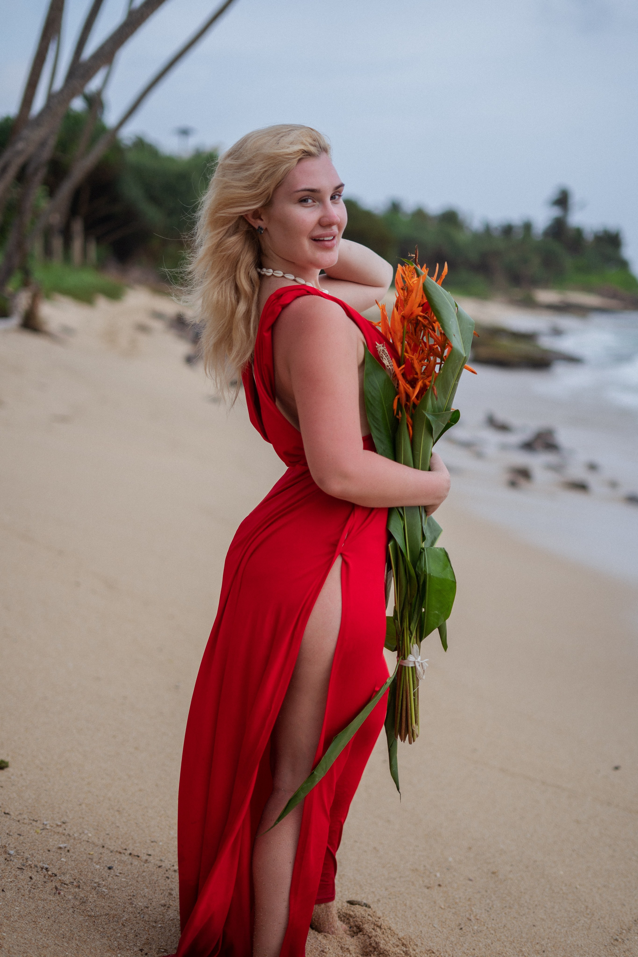 a beautiful blonde in a flowing red dress by the water