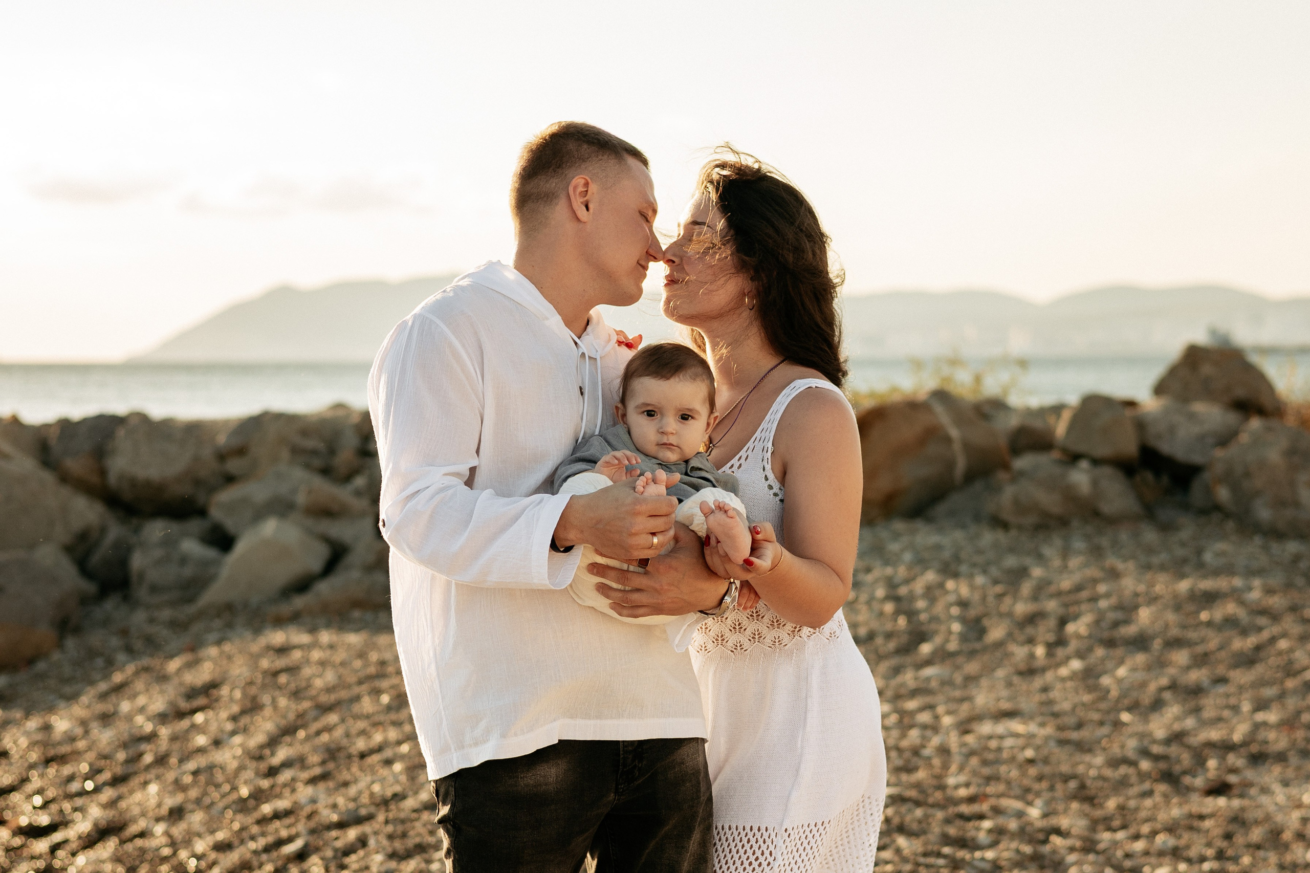 Нежные объятия трех человек на фоне золотого заката