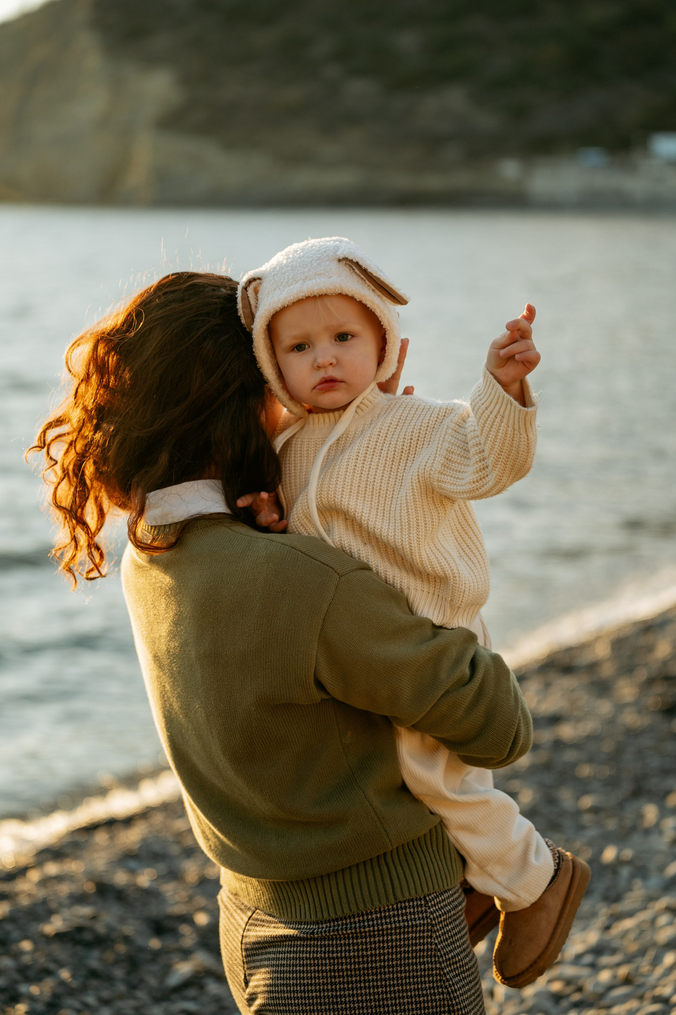 Love story семьи у моря в Новороссийске. Мама и папа обнимаются, пока дети играют на берегу. Фотосессия на побережье от фотографа из Новороссийска.