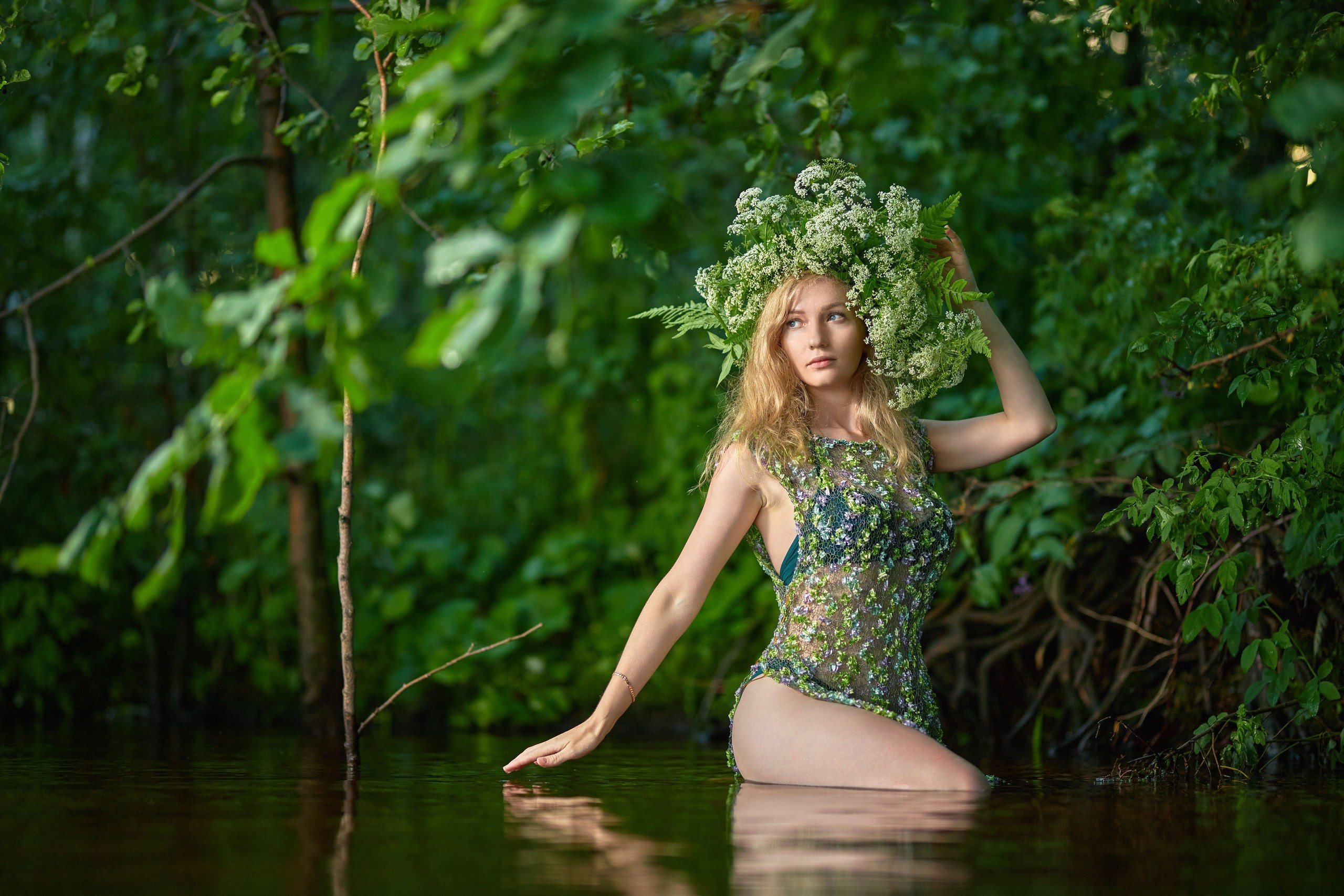 Девушка с венком на голове в прозрачной одежде стоит в воде