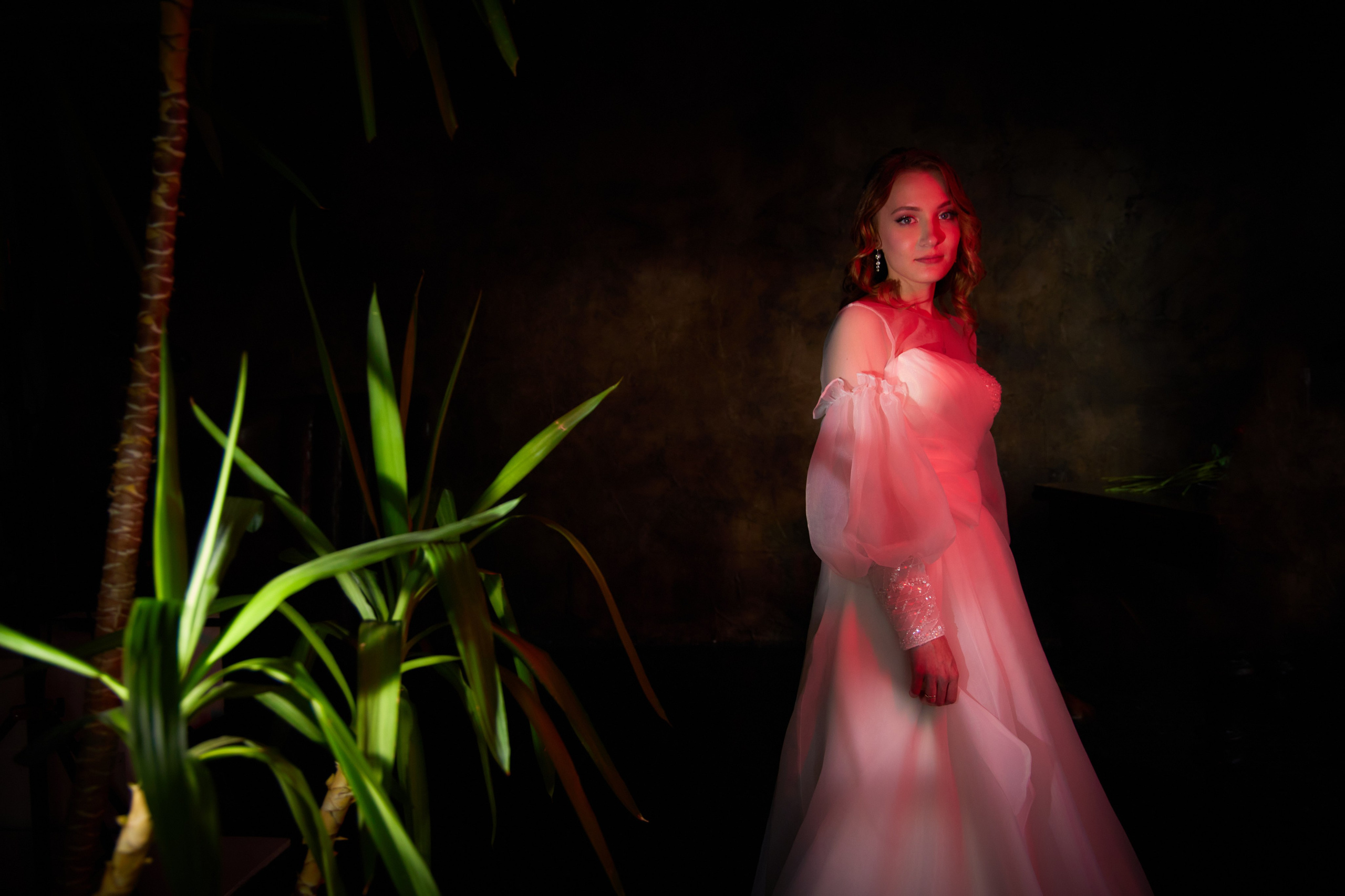 зеленые листья деревьев и невеста с красной подсветкой платья