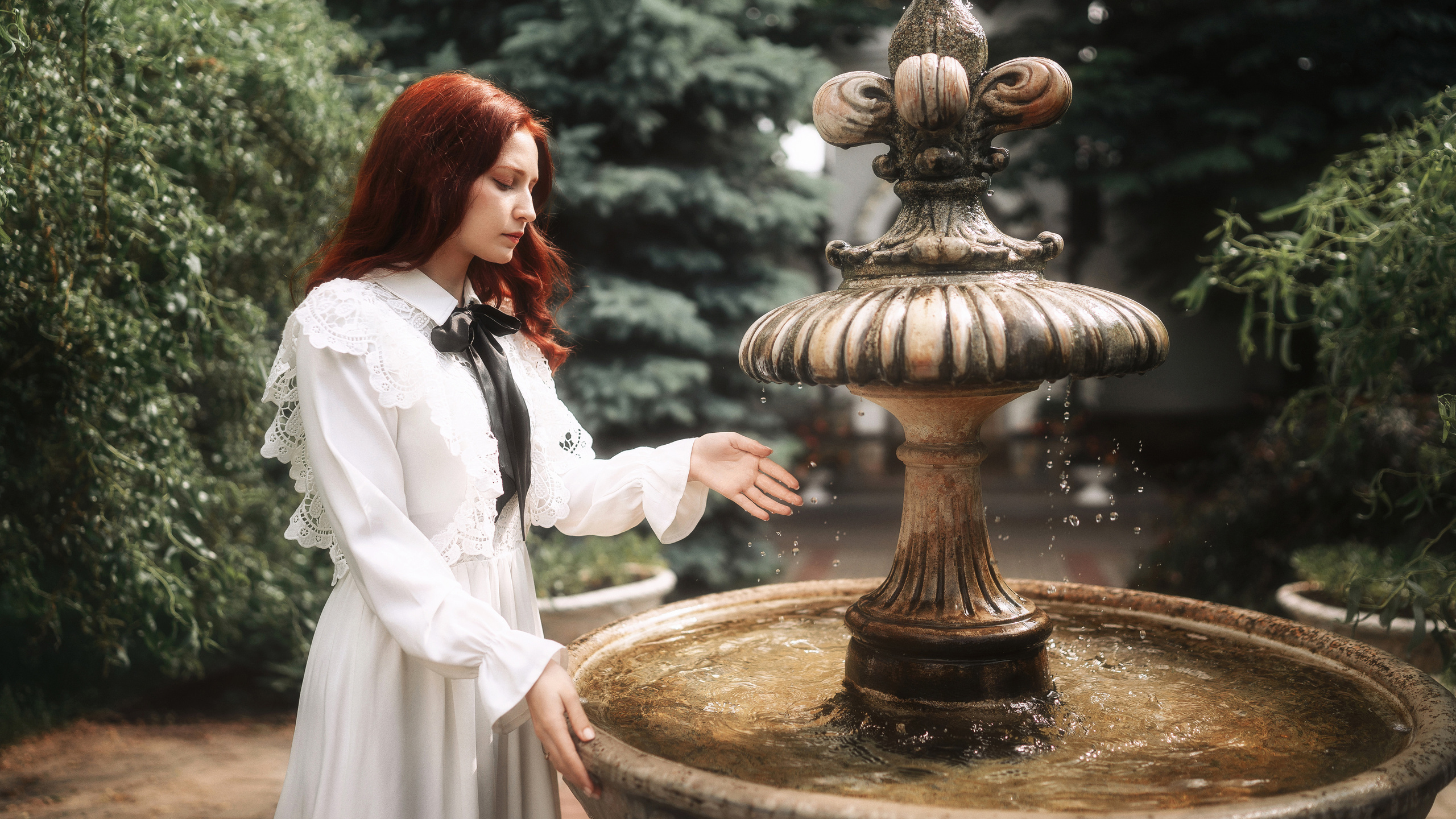 Рыжая девушка стоит у фонтана. Фотография Романа Яковенко