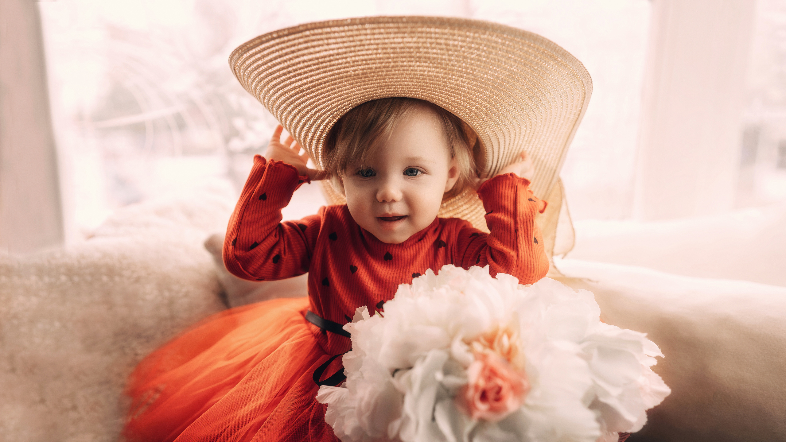 Девочка в красном платье сидит на подоконнике и держит соломенную шляпу. Автор: Роман Яковенко