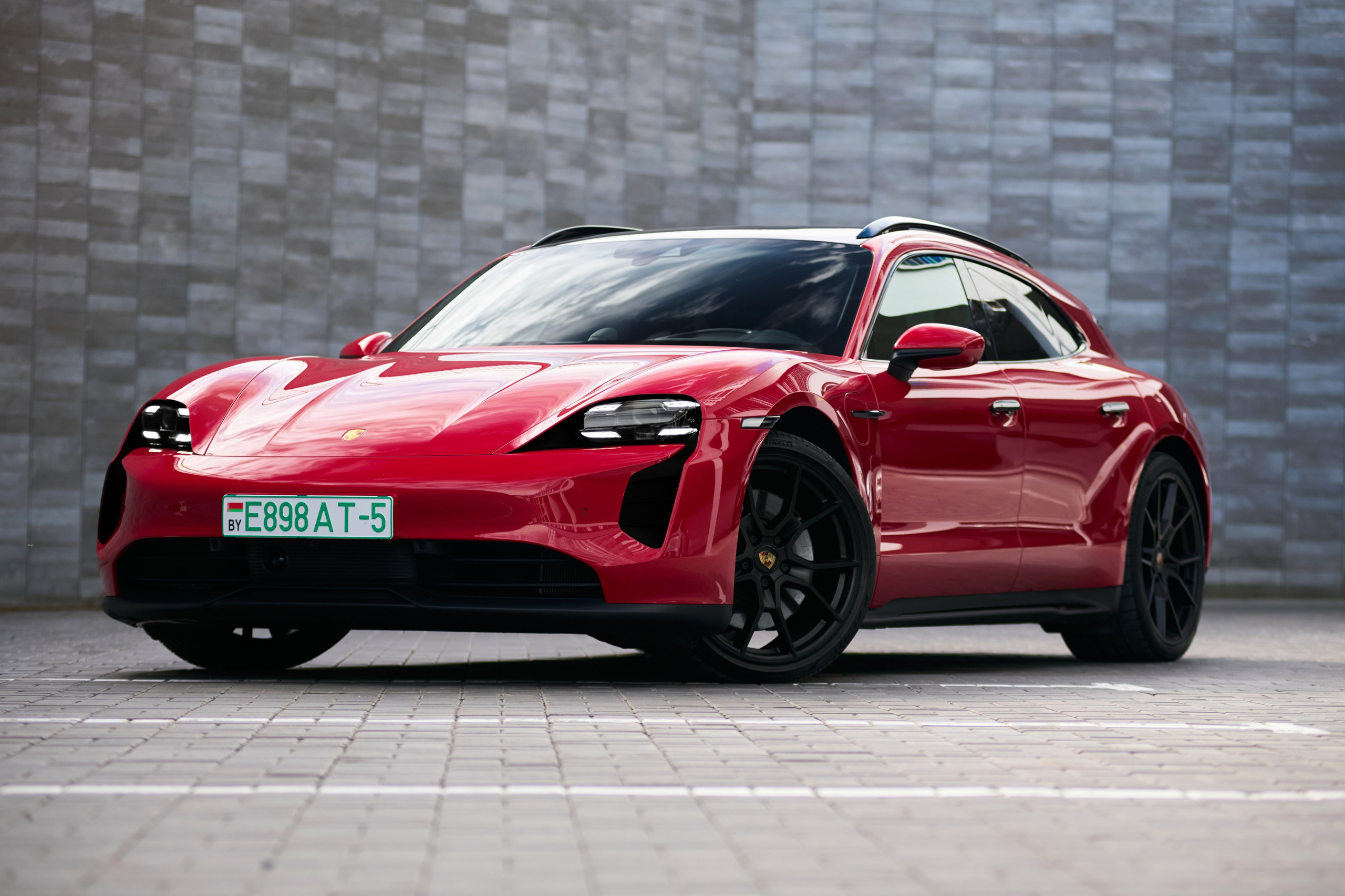 Красный Porsche Taycan GTS с переднего правого ракурса на парковке