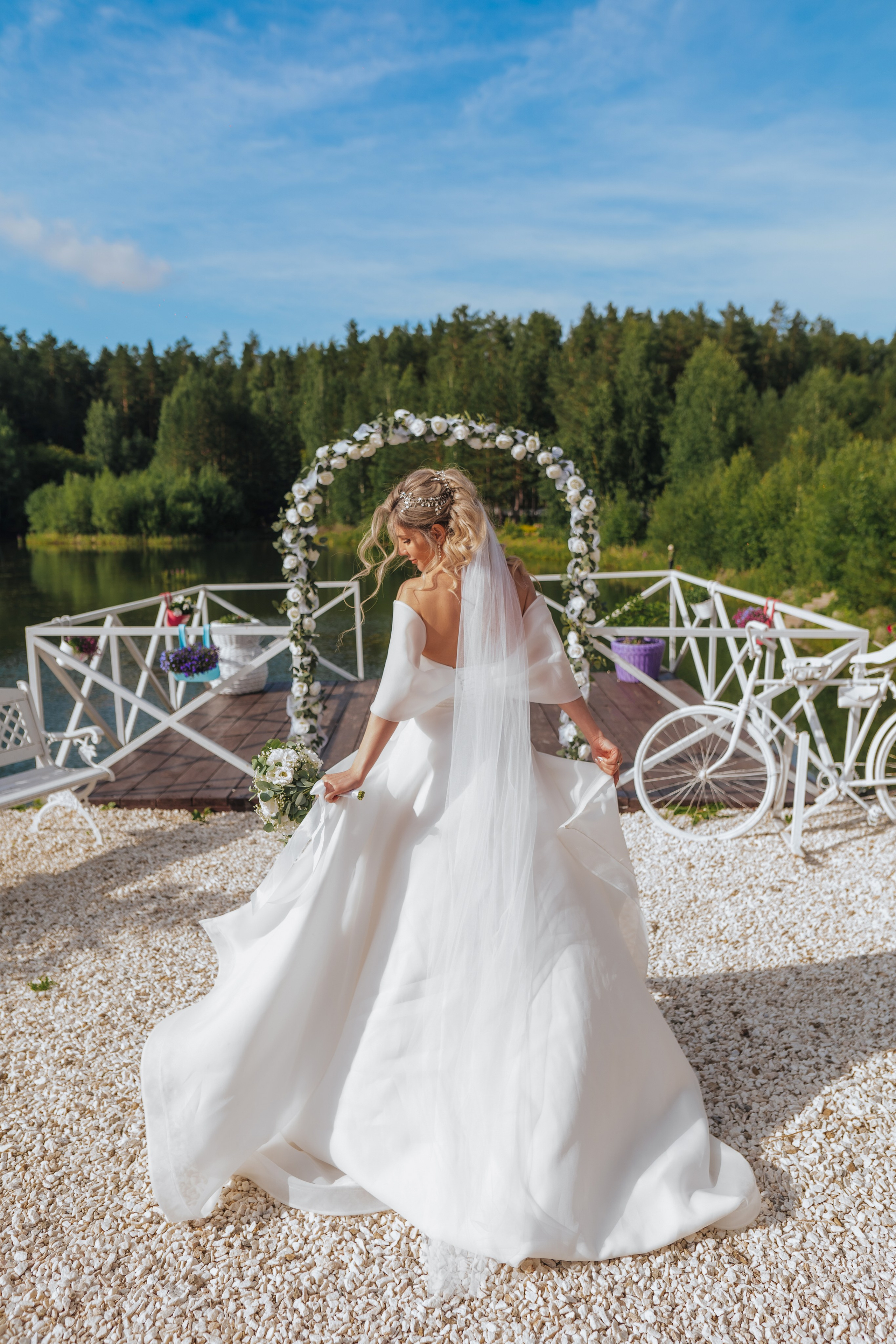 Свадебная фотография, невеста на фоне арки и озера